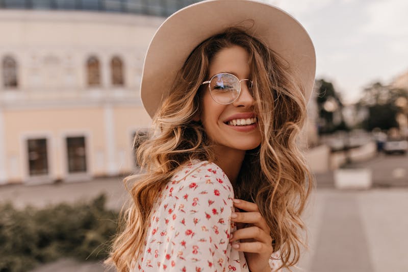 woman with wavy hair wearing a big hat