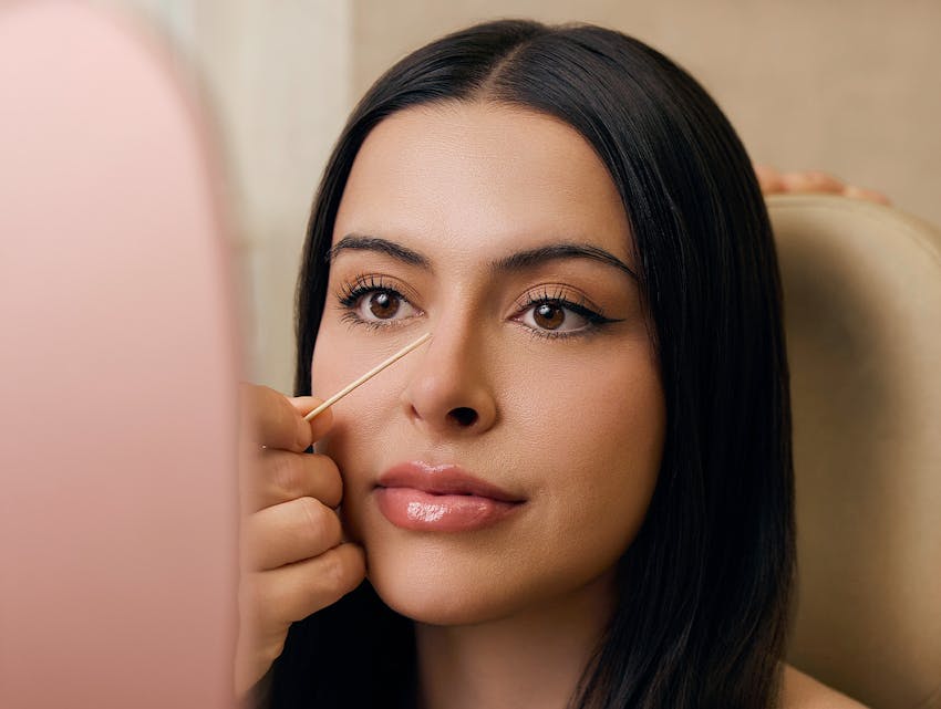 woman looking at her nose in a hand mirror