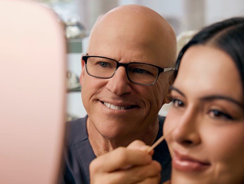 doctor showing a patient her face in a hand mirror