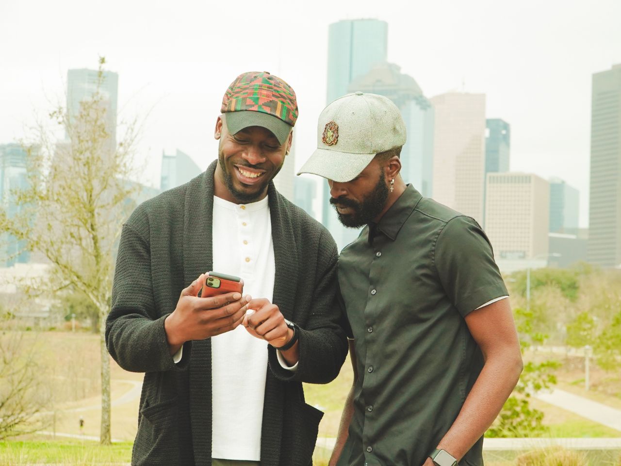 A man is showing his friend how to send money to Nigeria on his cell phone.