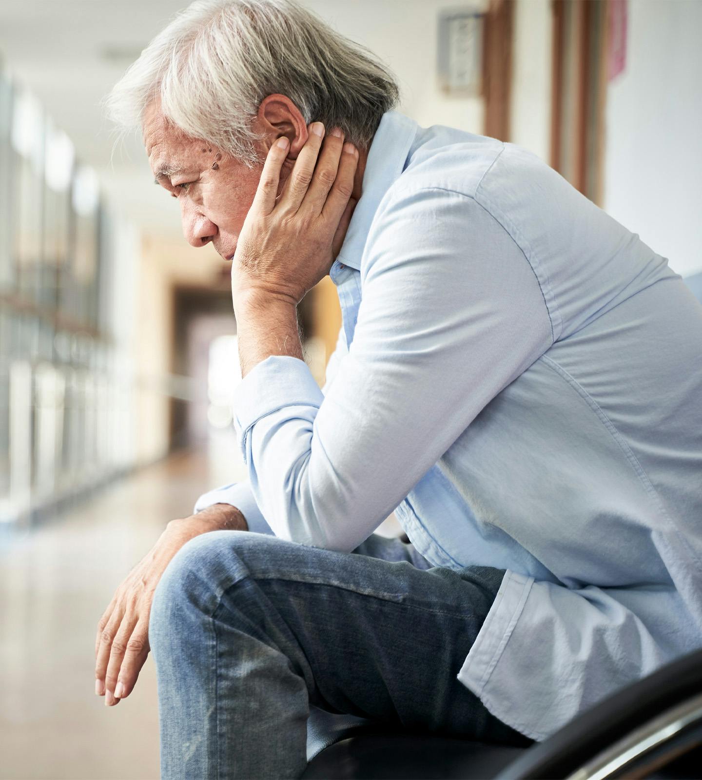 older man holding his head in his hand