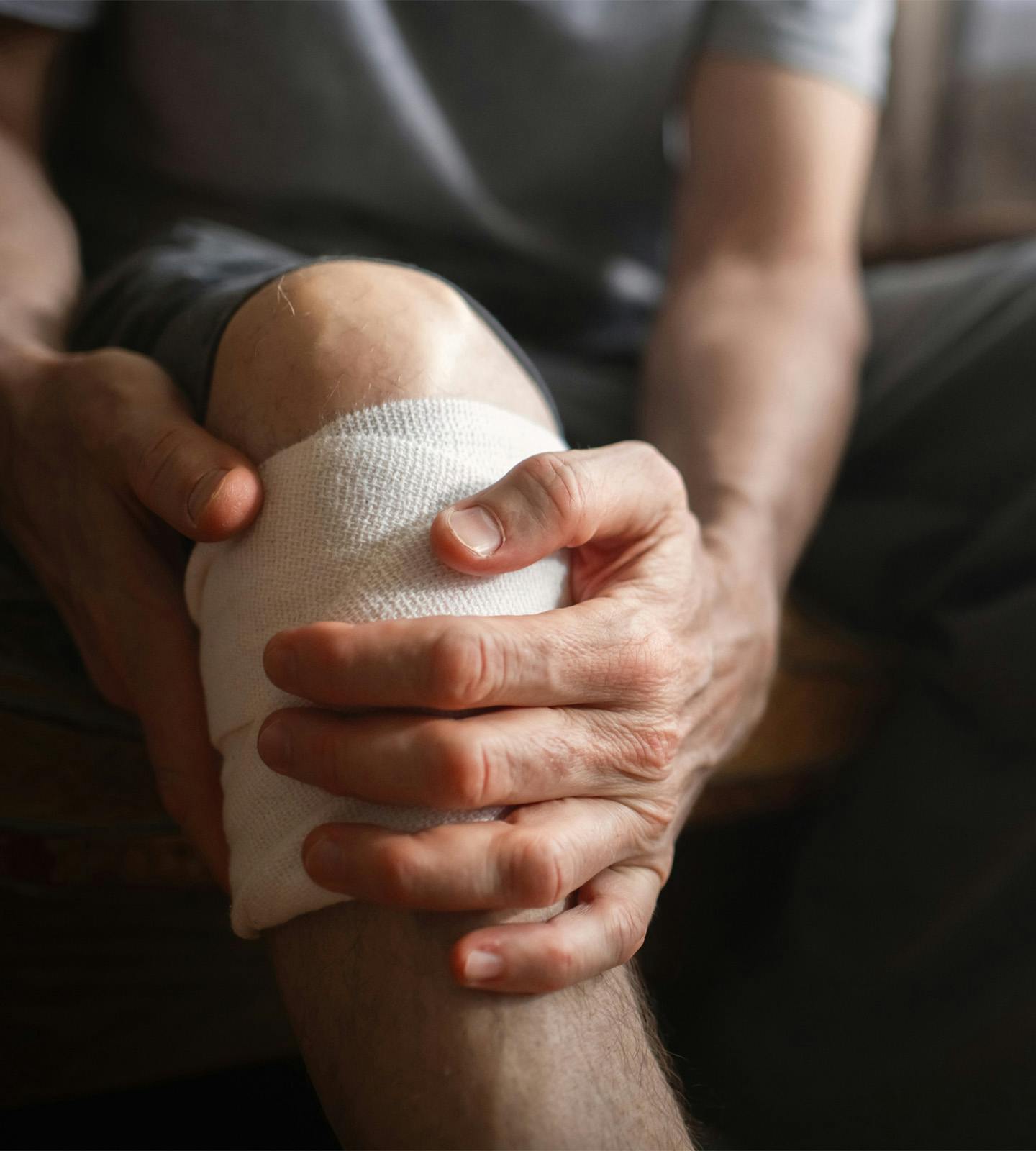 person holding their knee that is wrapped in gauze