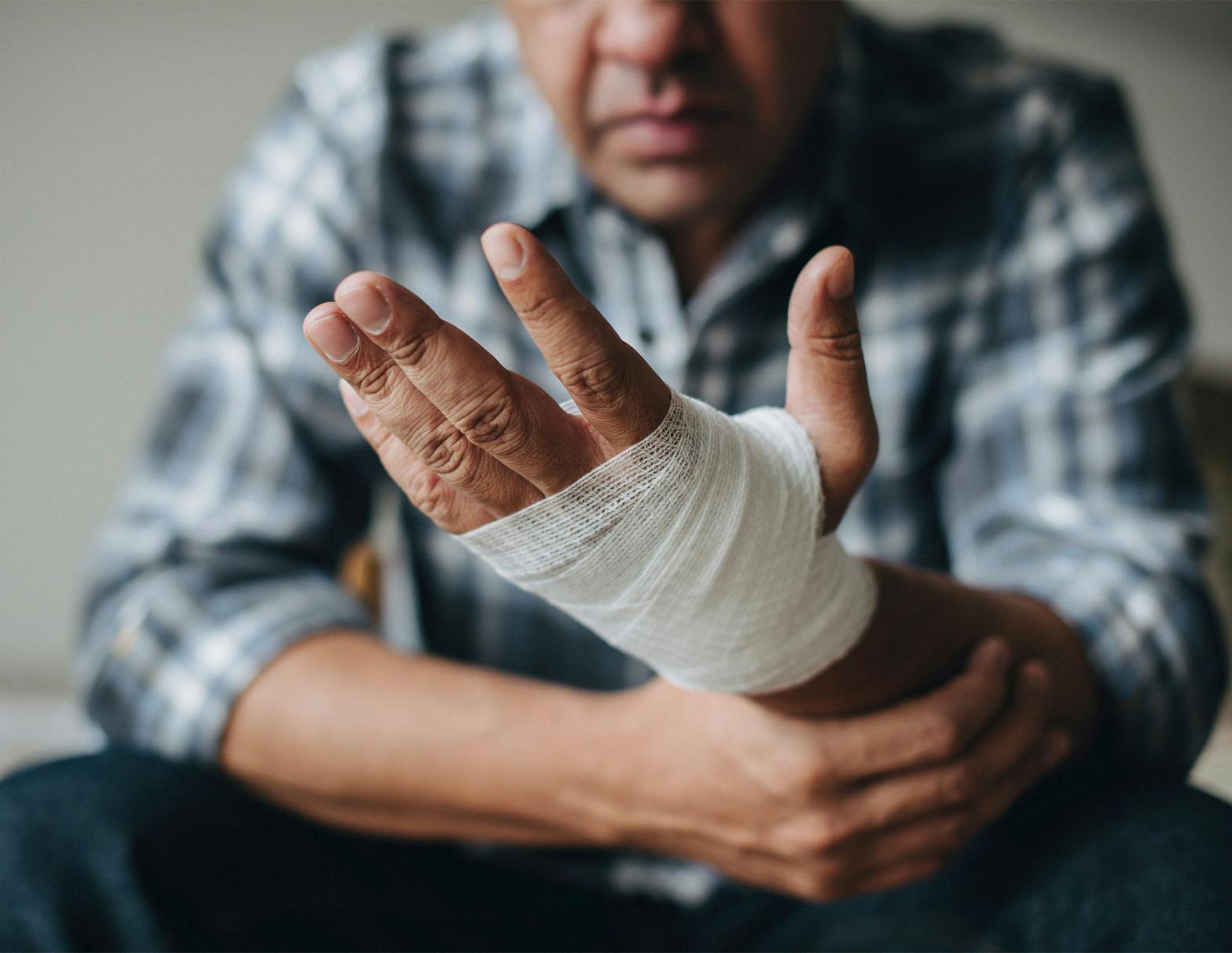 man holding his hand that is wrapped in gauze