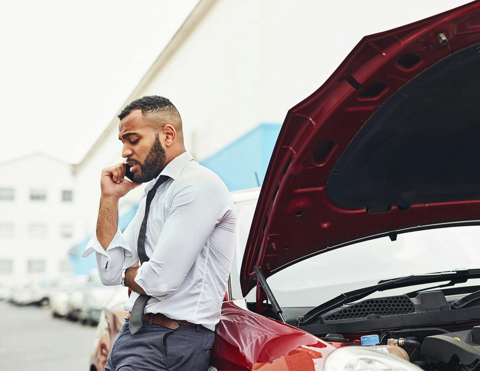 man on the phone, leaning against a car