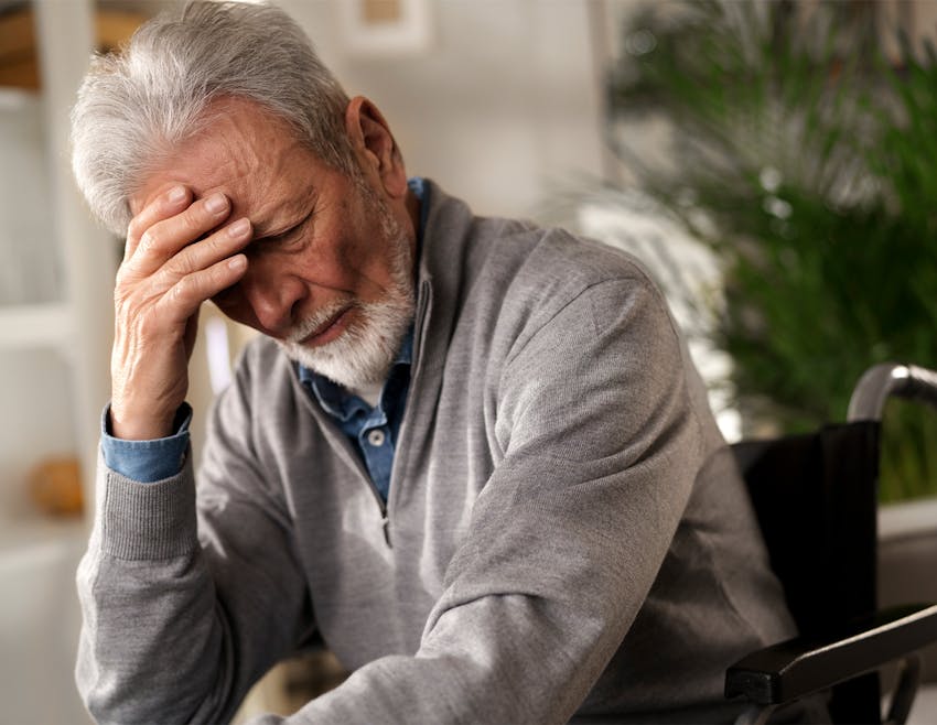 older man holding his head in his hand