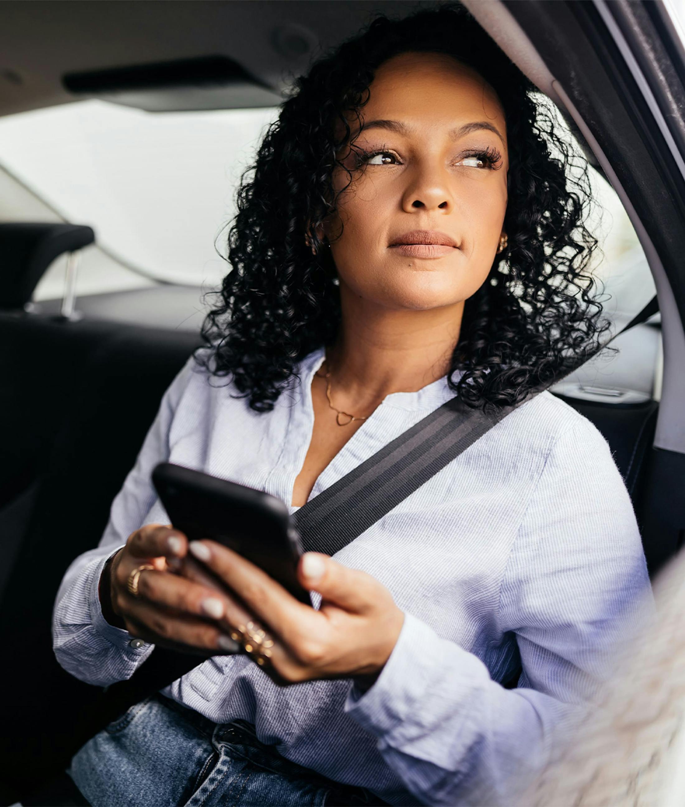 woman on her phone, looking out a car window