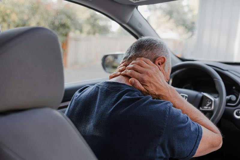 man holding the back of his neck after a car accident