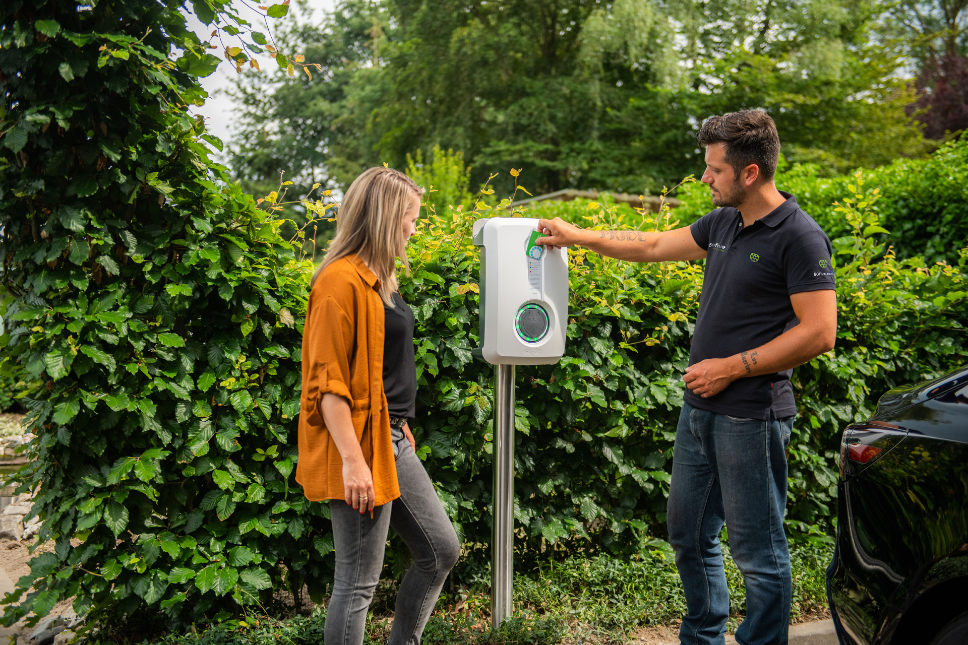 Un installateur de 50Five présente à un client un chargeur EVBox sur socle dans une résidence.