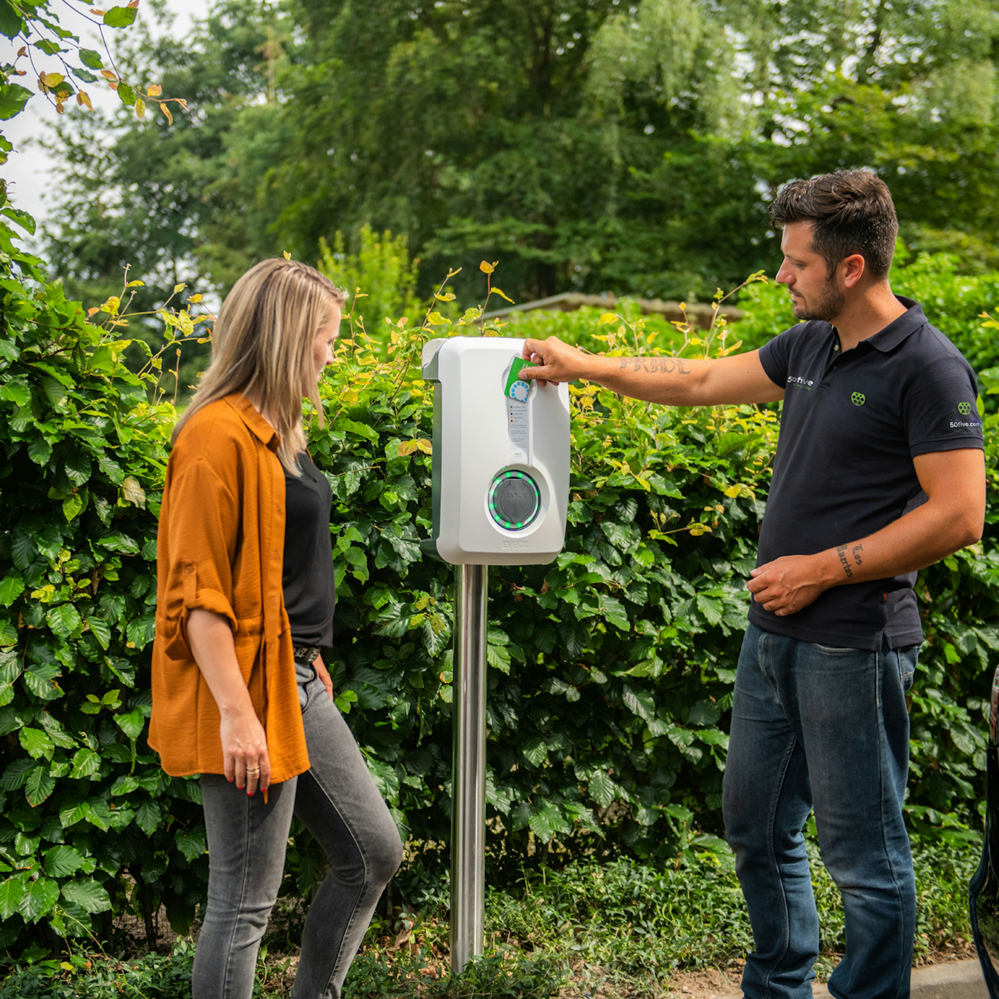 Un installateur de 50Five présente à un client un chargeur EVBox sur socle dans une résidence.