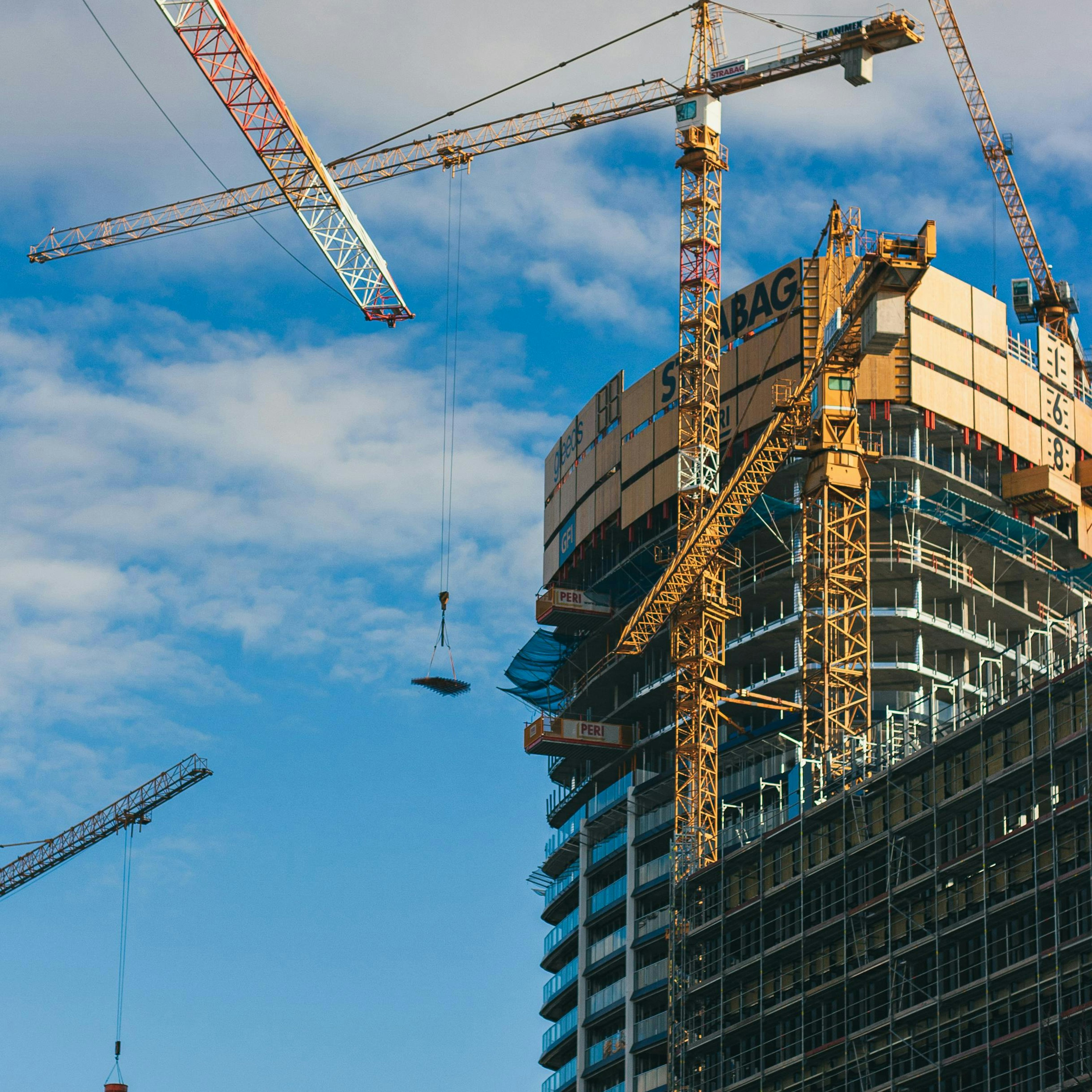 Des grues à tour autour d'un gratte-ciel en construction