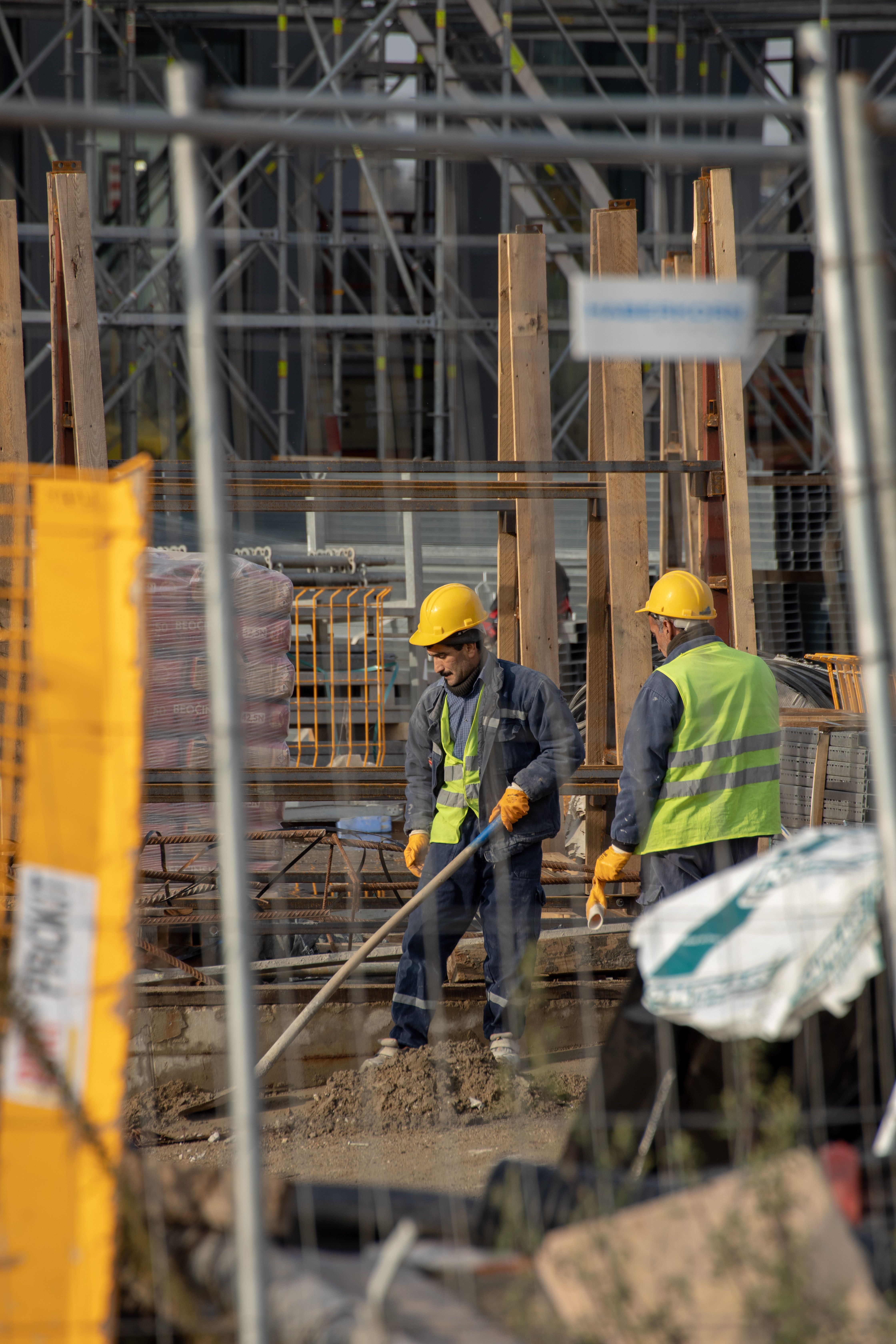 Des ouvriers du bâtiment en gilets haute visibilité derrière la clôture du chantier