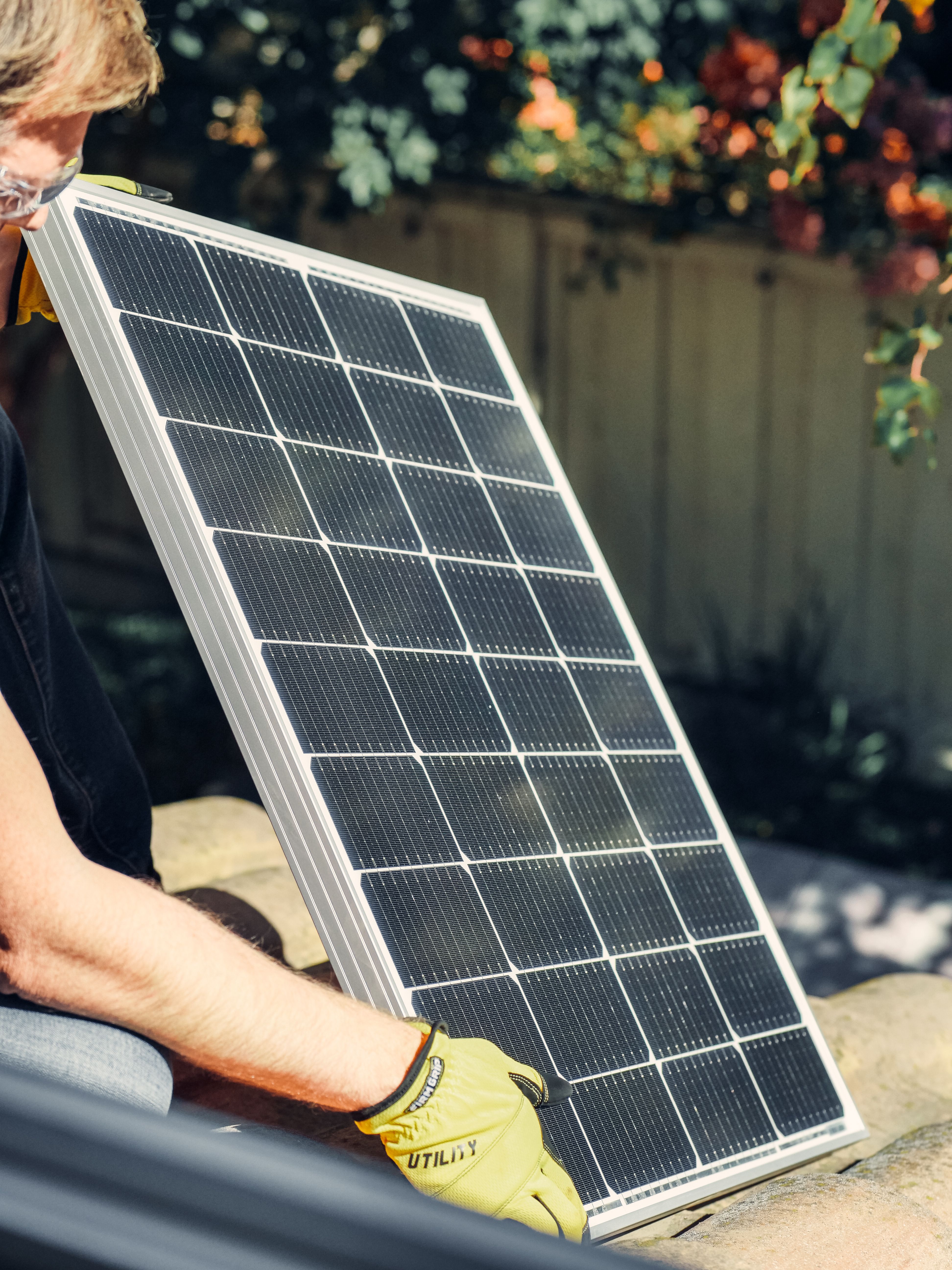Un installateur en train de poser un panneau solaire sur un toit en tuiles