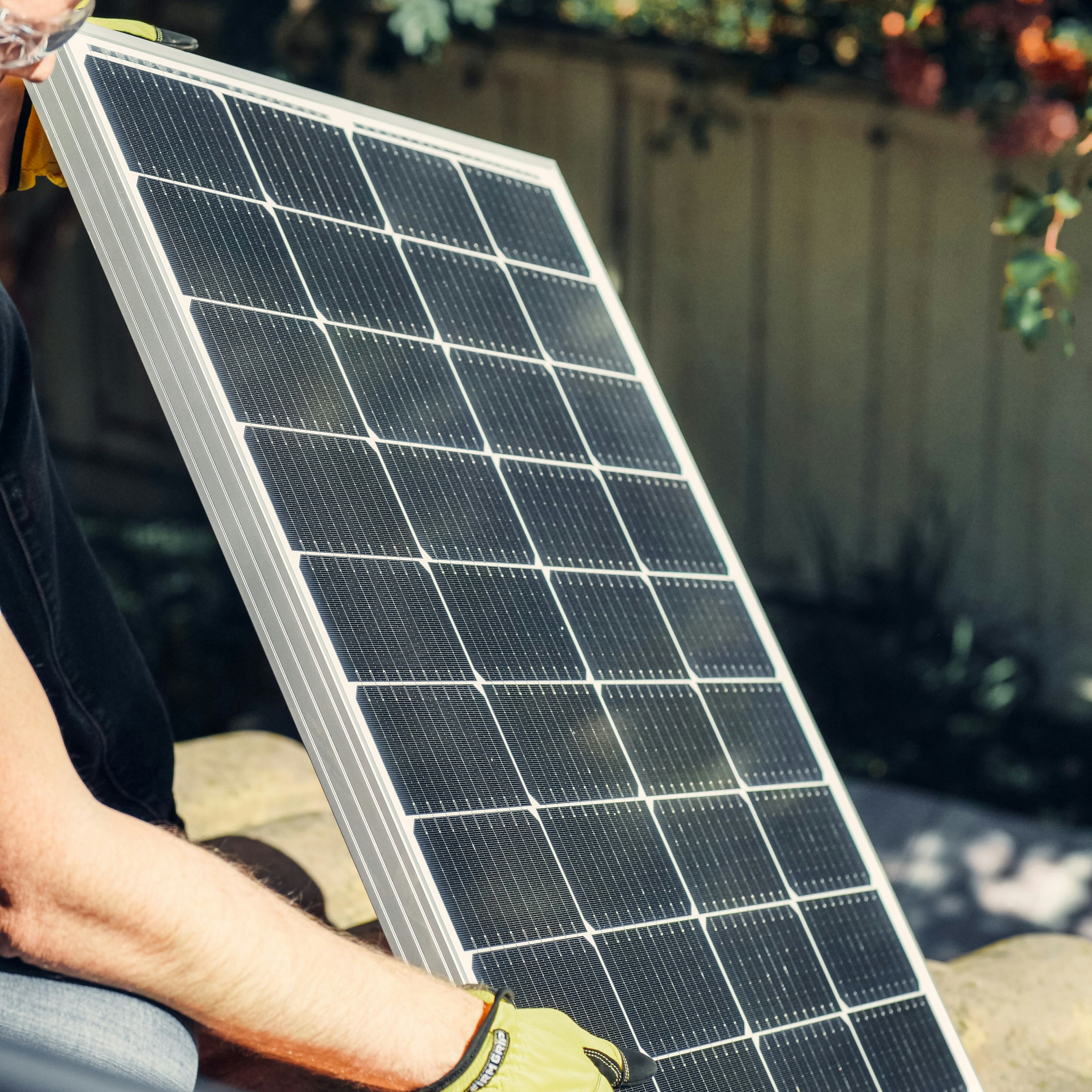 Un installateur en train de poser un panneau solaire sur un toit en tuiles