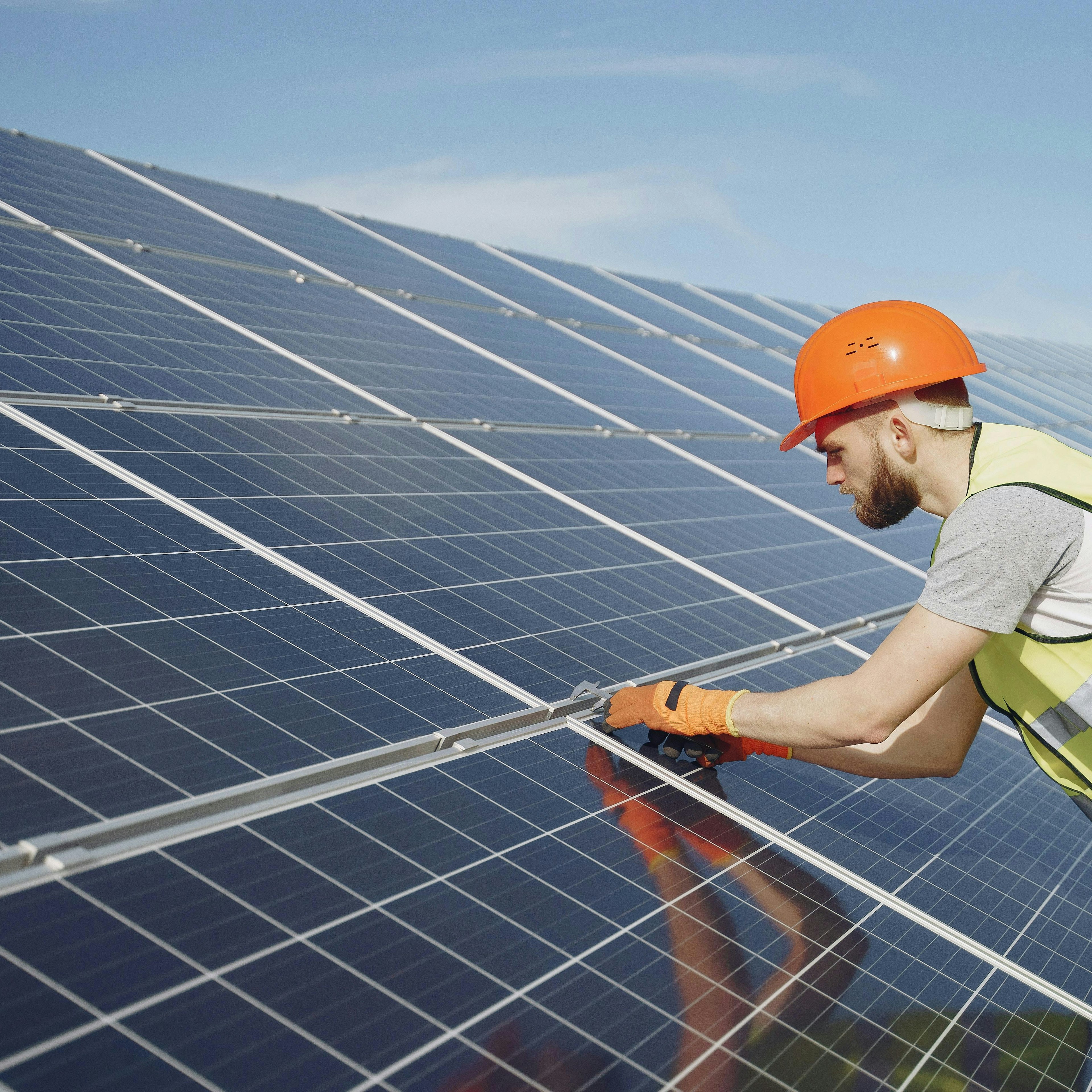 Worker in hi-vis vest installing solar panels