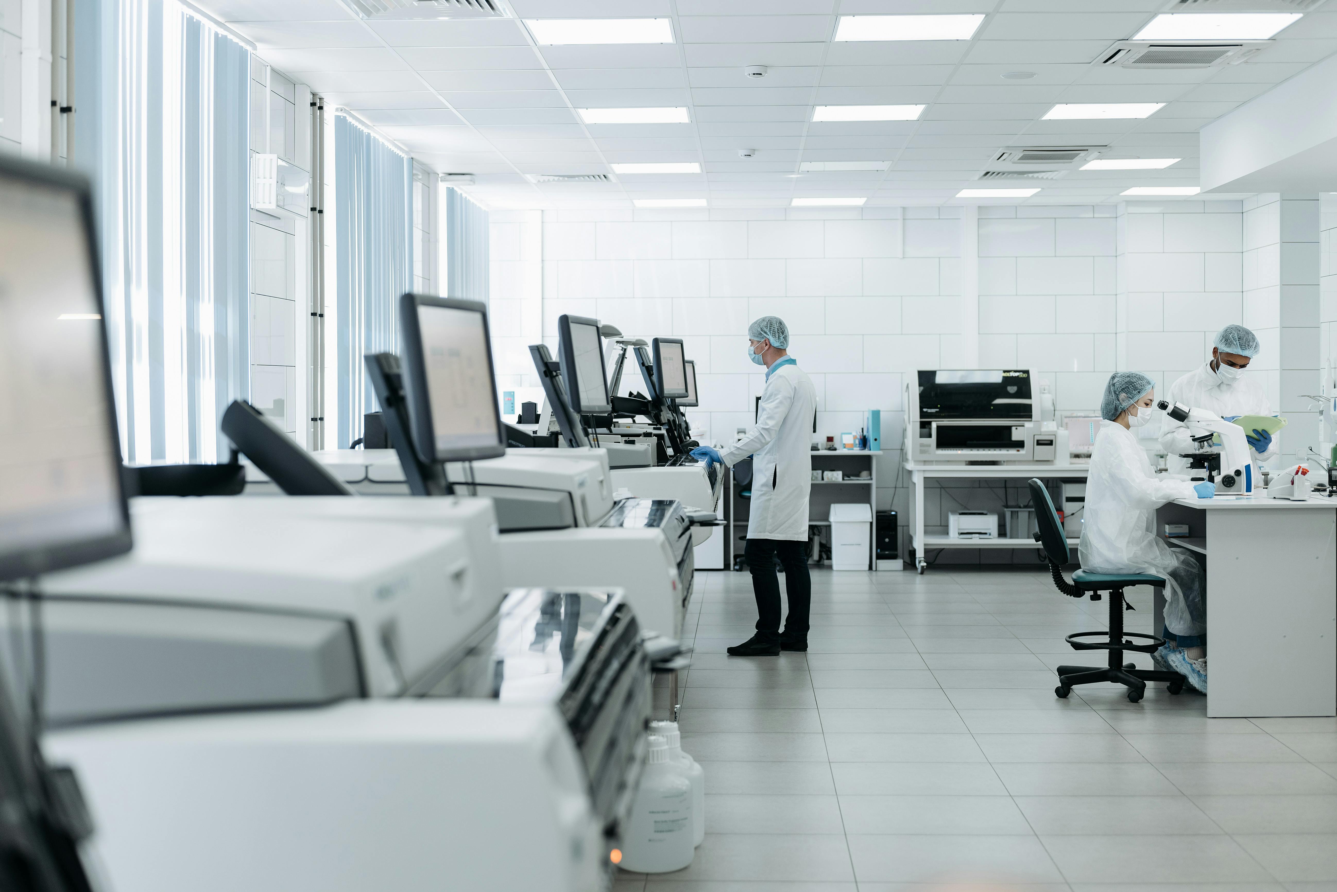 Lab staff working at analysers and a microscope