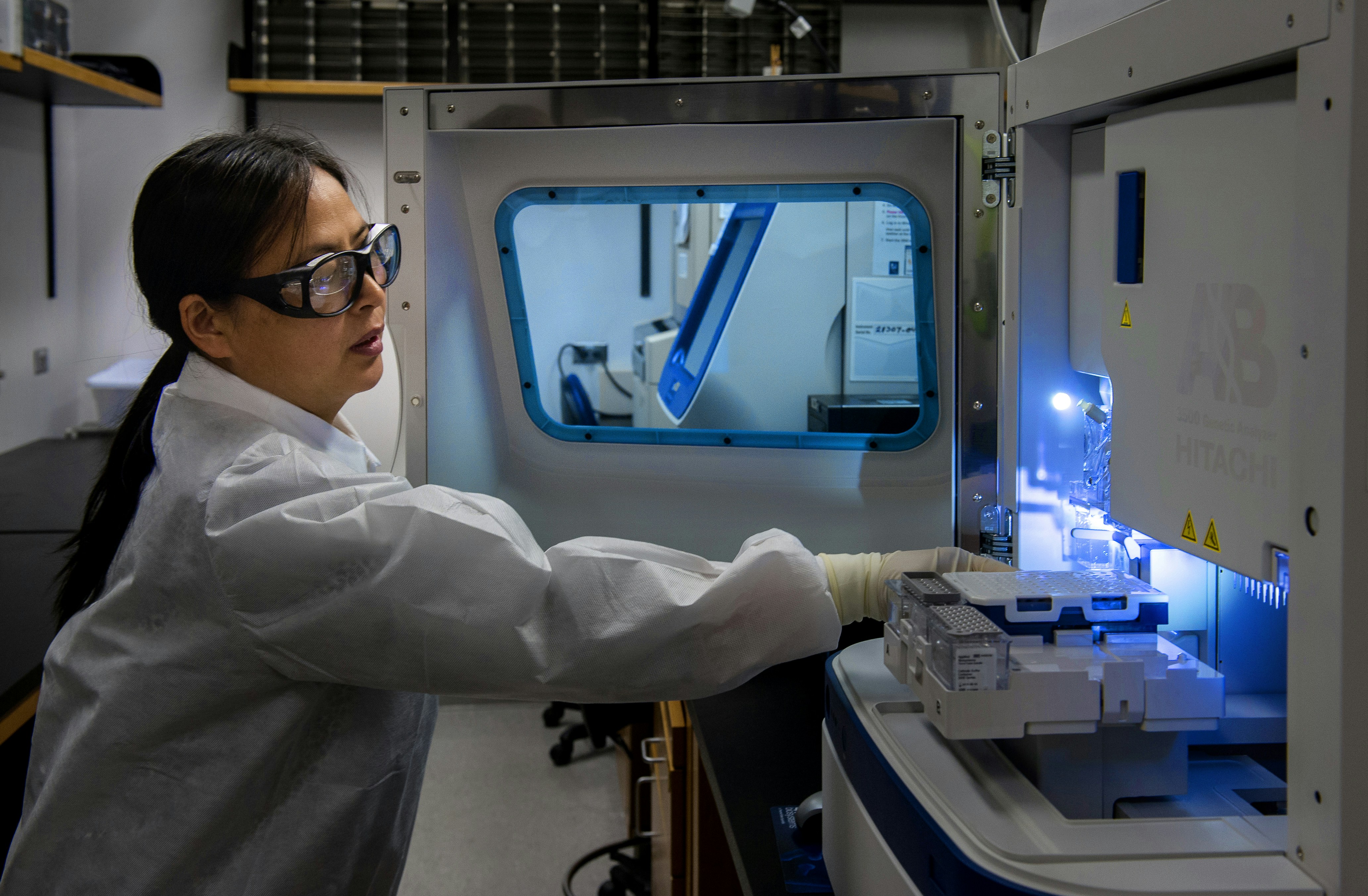 Un scientifique charge des portoirs d'échantillons dans un analyseur de laboratoire
