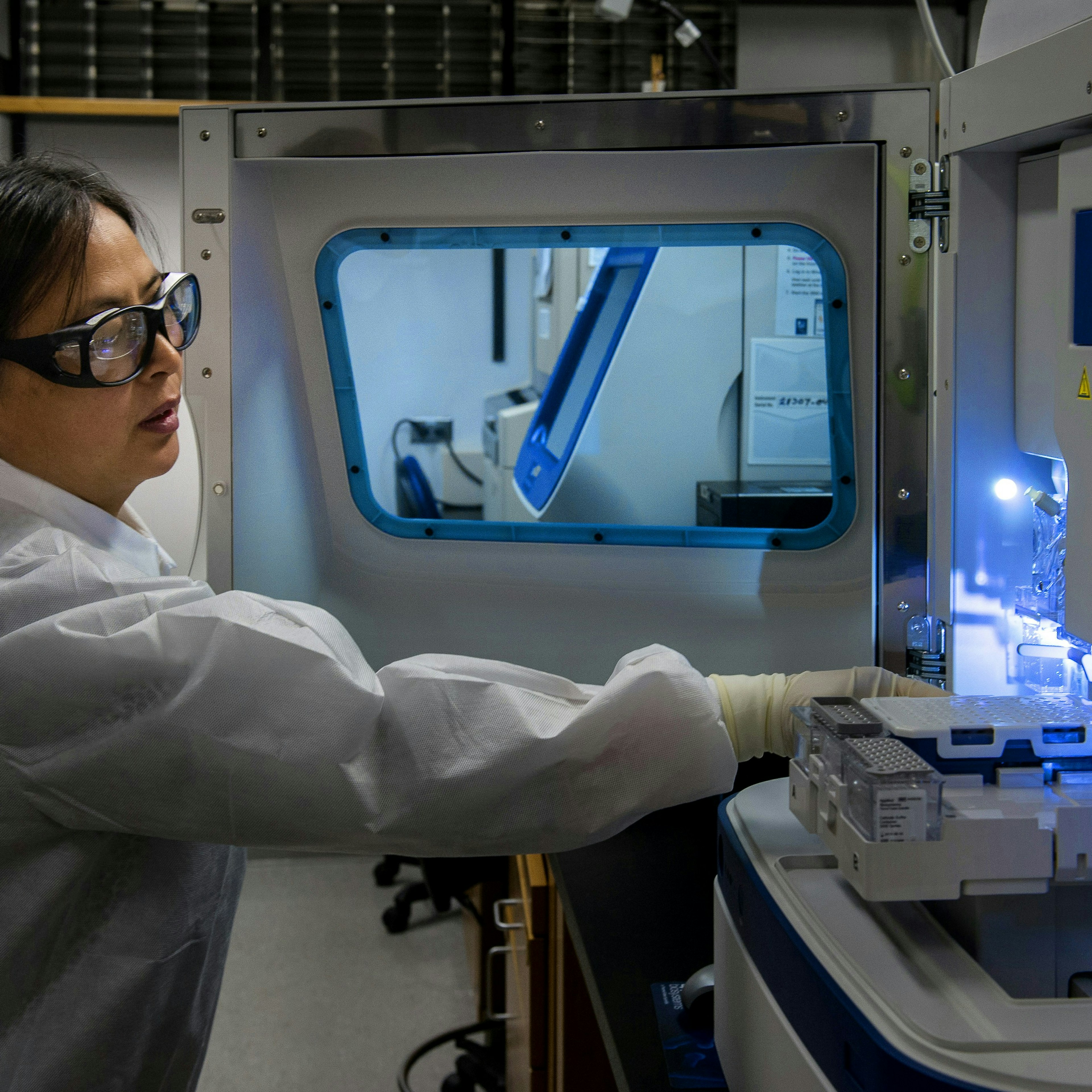 Un scientifique charge des portoirs d'échantillons dans un analyseur de laboratoire