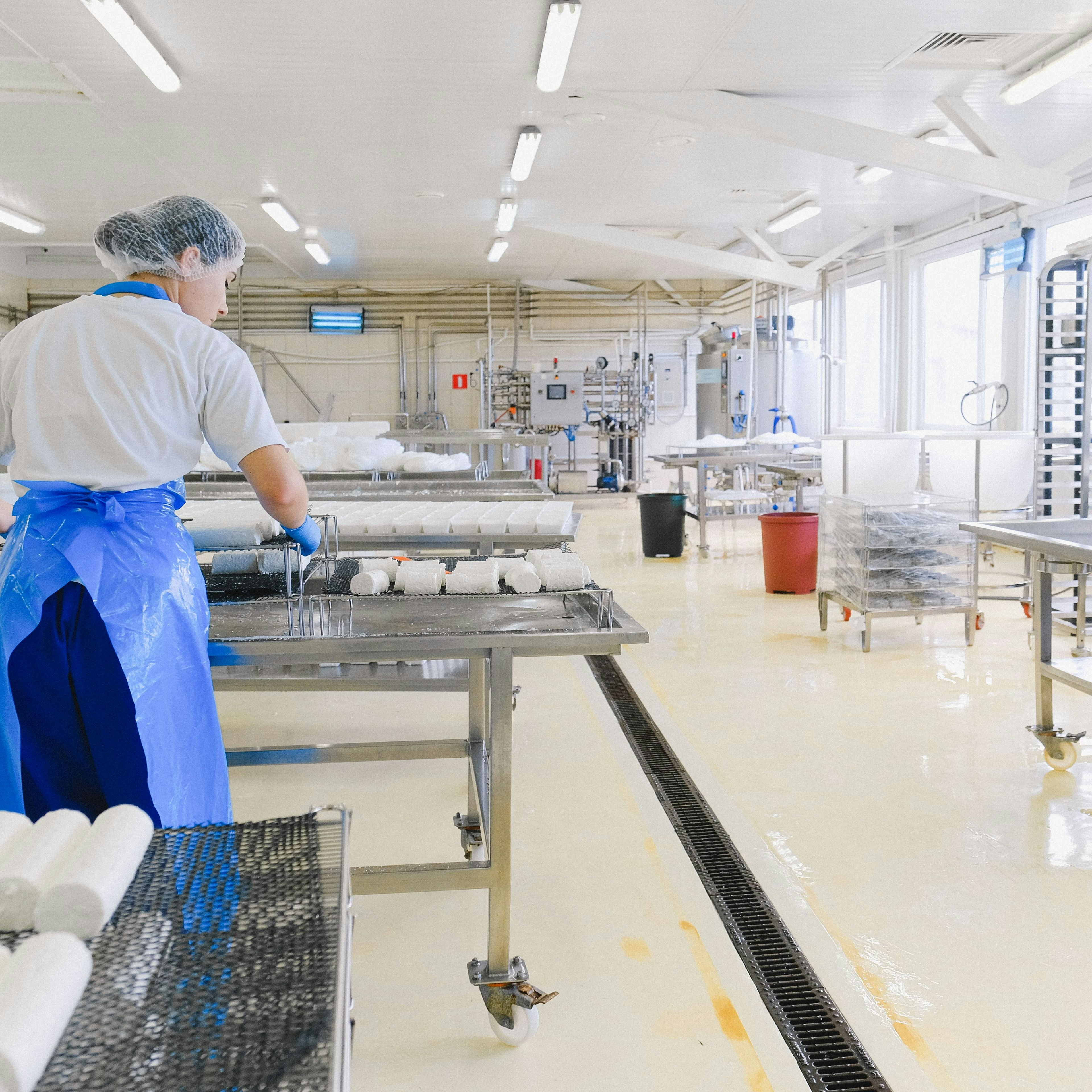 Un ouvrier manipulant des rouleaux de fromage dans un atelier de production