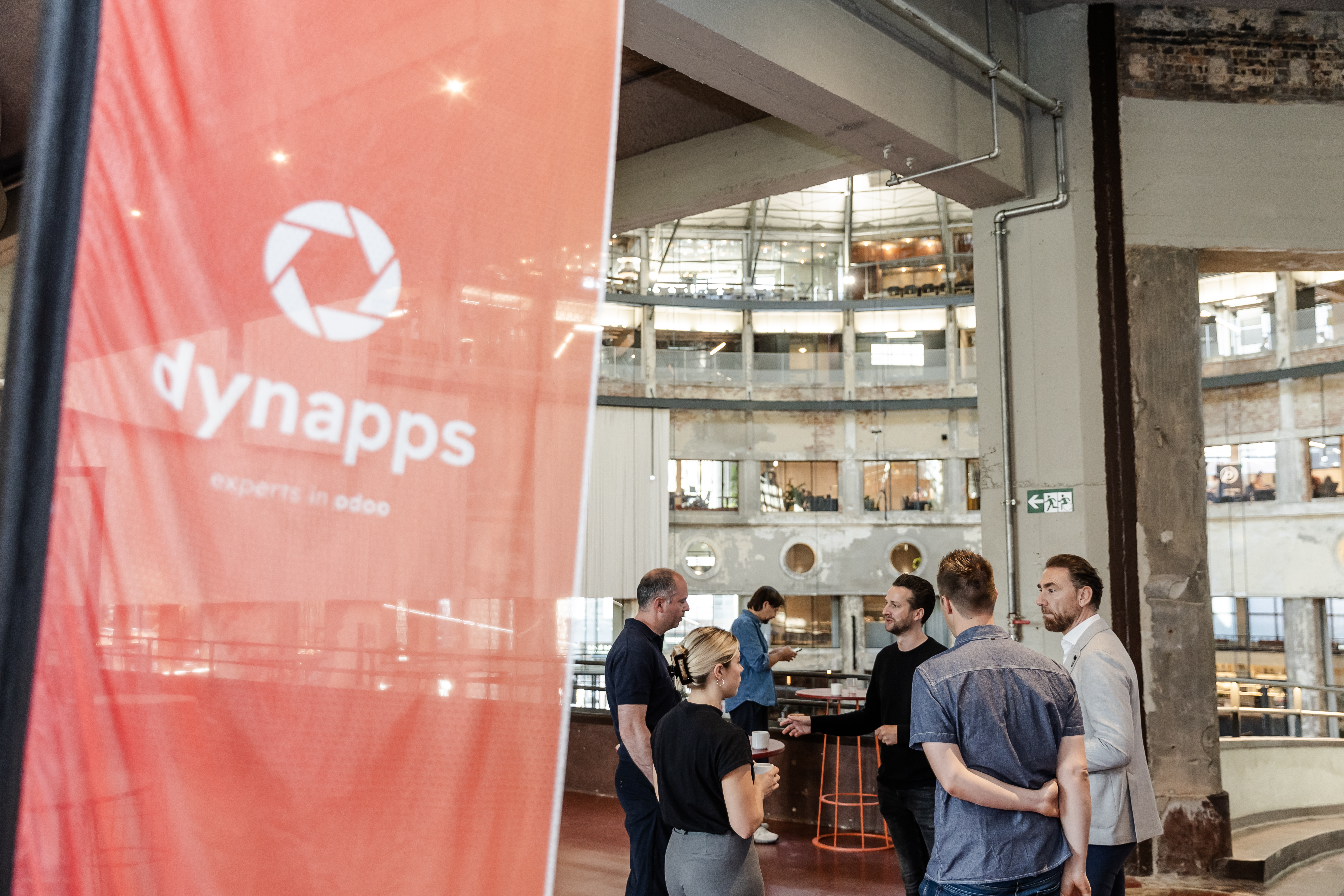 Des invités discutent près d'une bannière Dynapps lors d'un événement