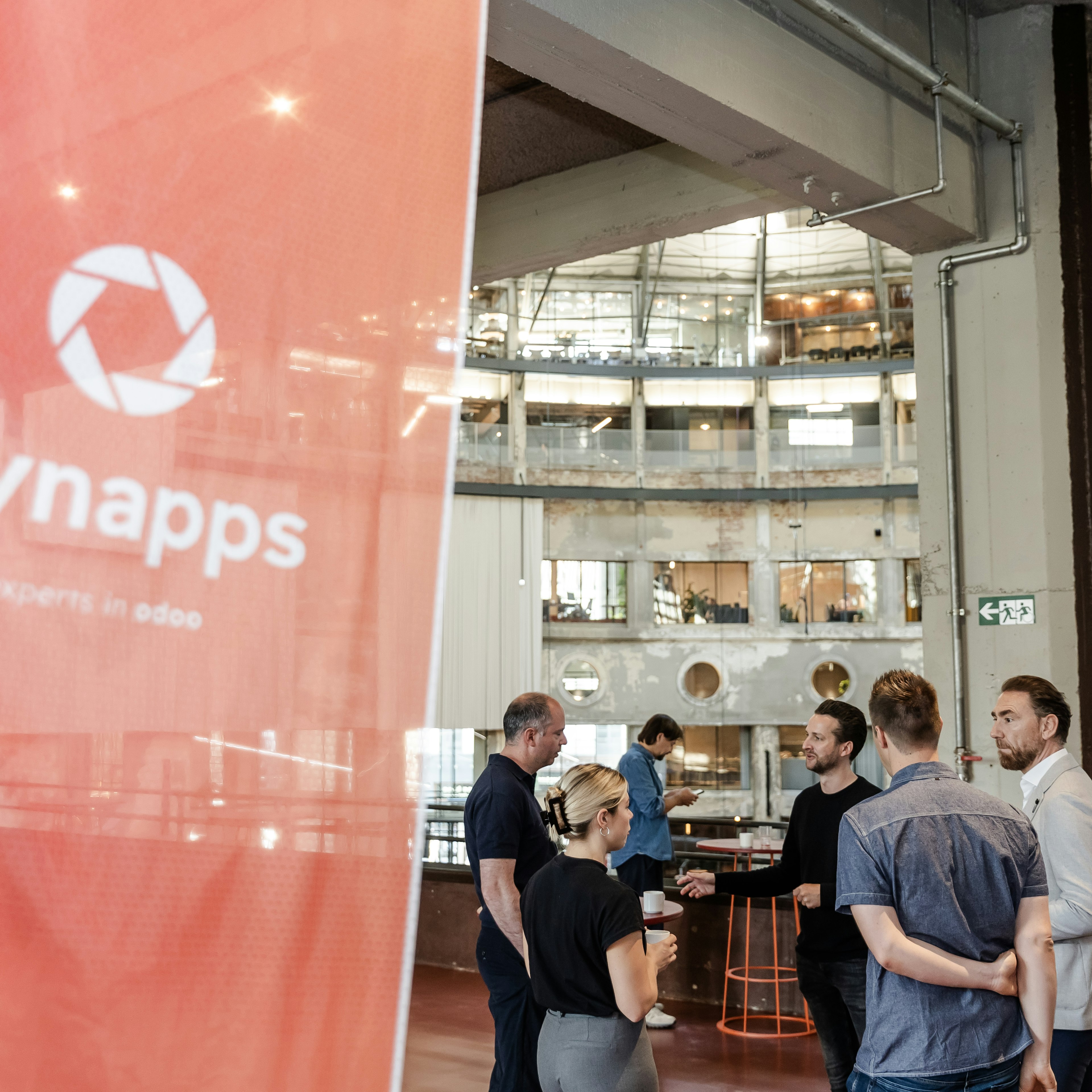 Des invités discutent près d'une bannière Dynapps lors d'un événement