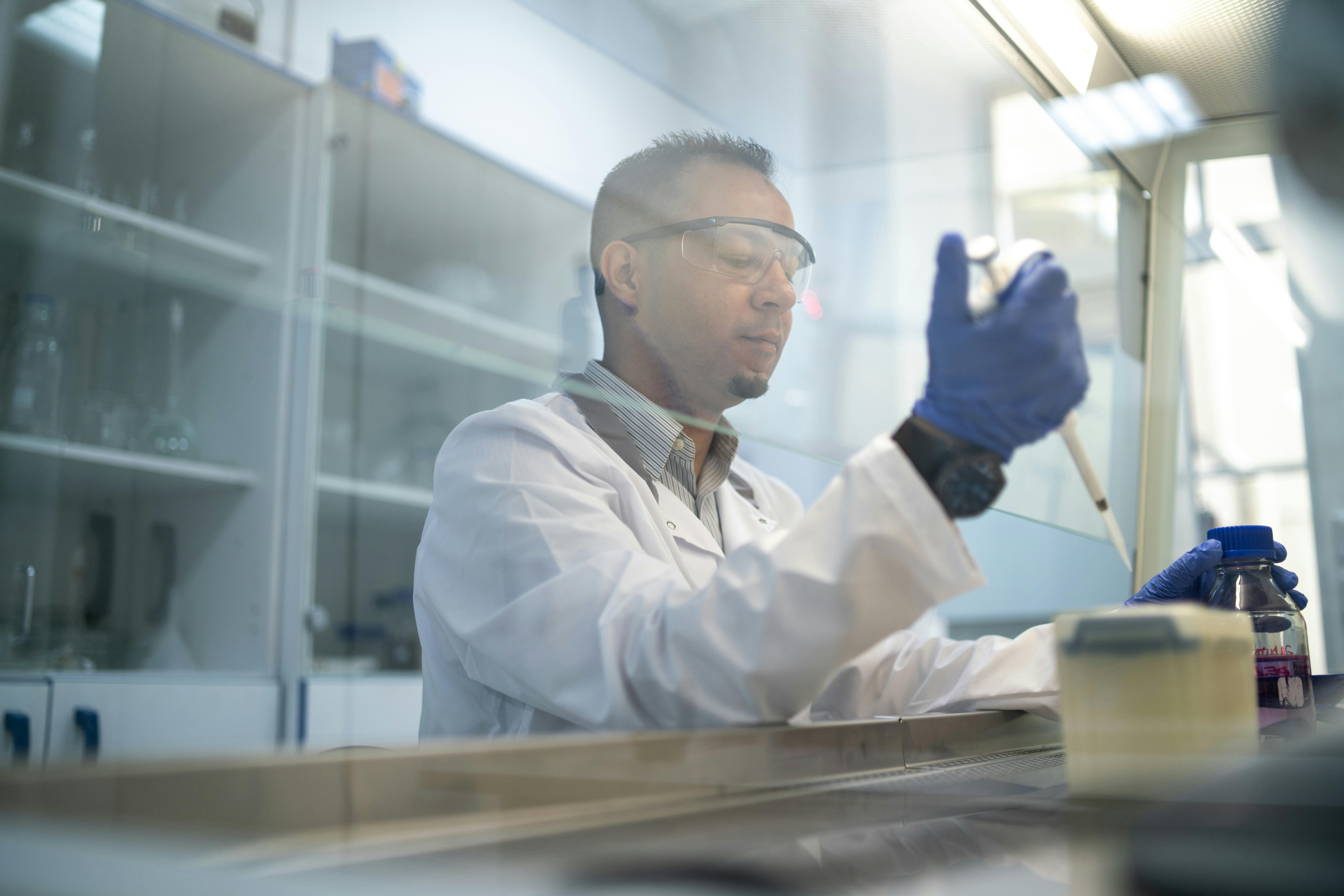 Un technicien de laboratoire utilisant une pipette derrière une hotte