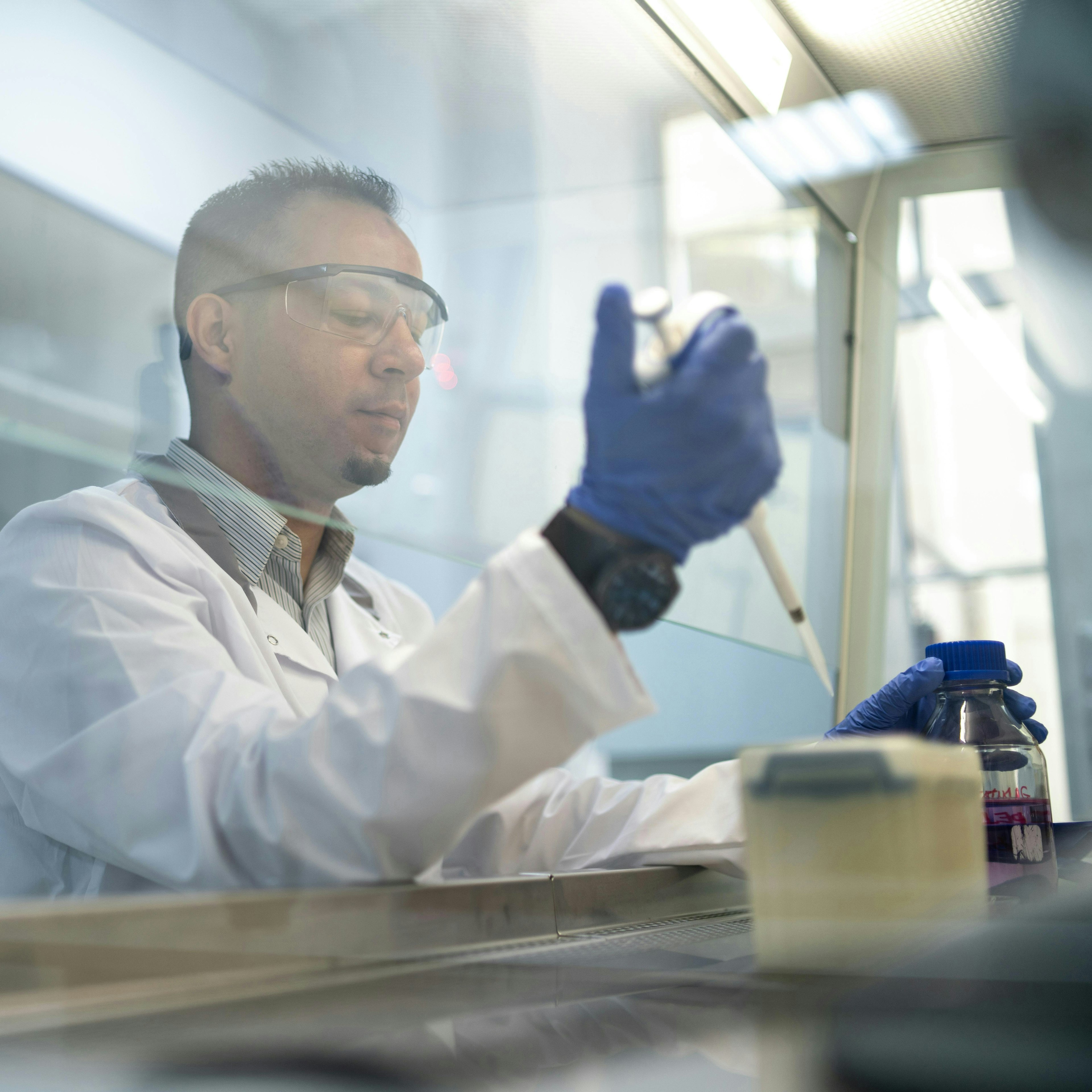 Un technicien de laboratoire utilisant une pipette derrière une hotte