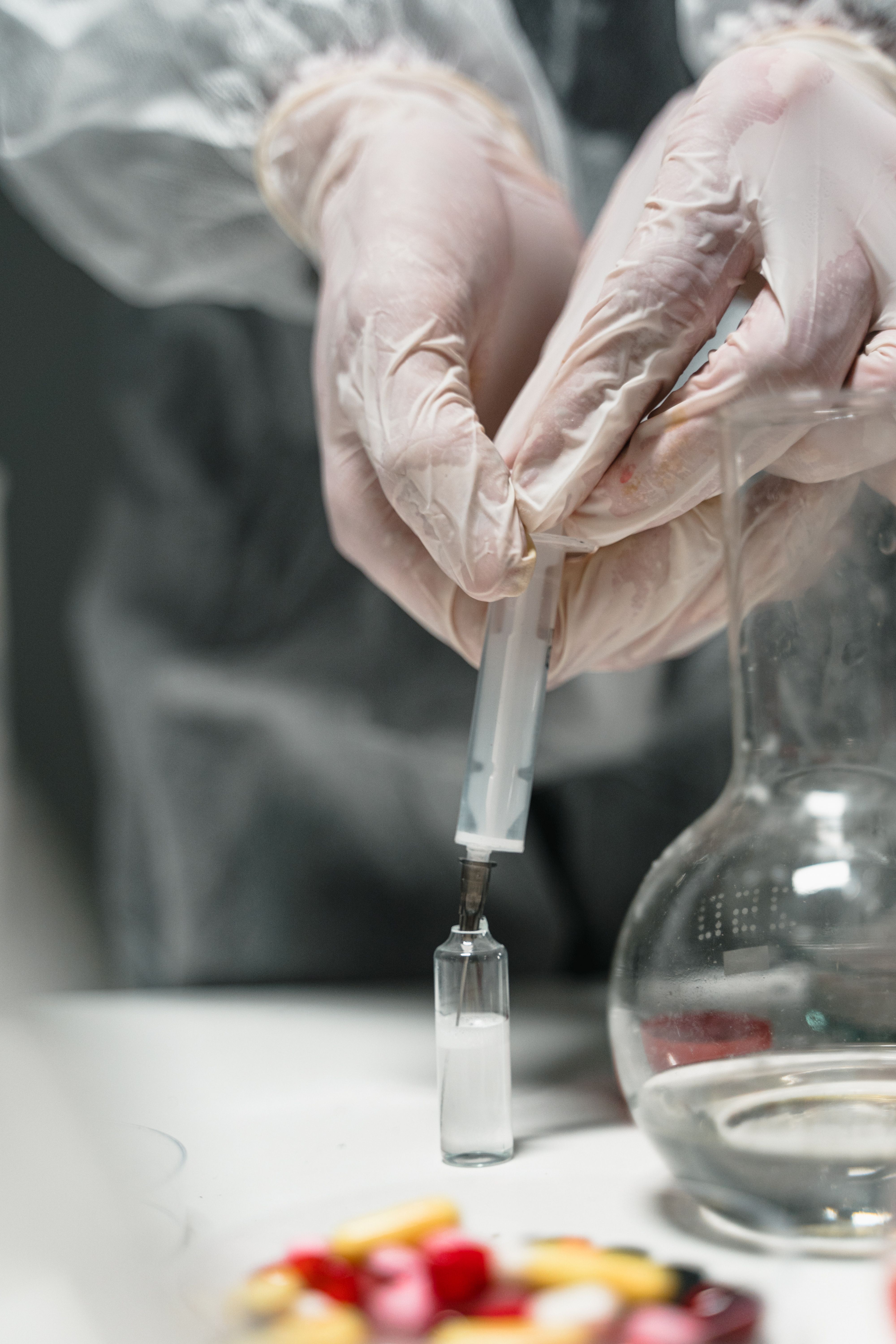 Laboratory technician pipetting liquid into a vial during pharmaceutical research.