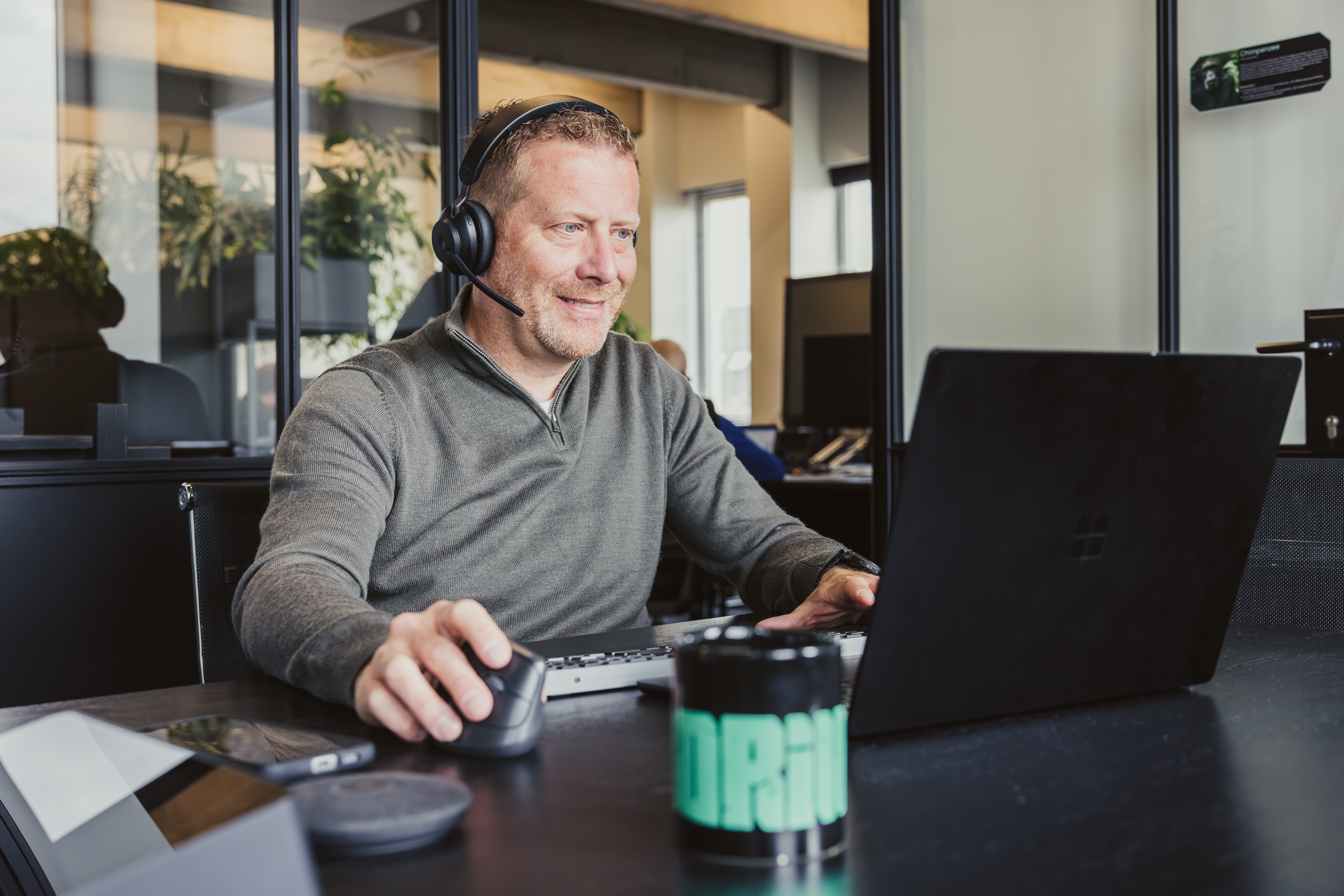 Man with a headset working at a laptop in an office