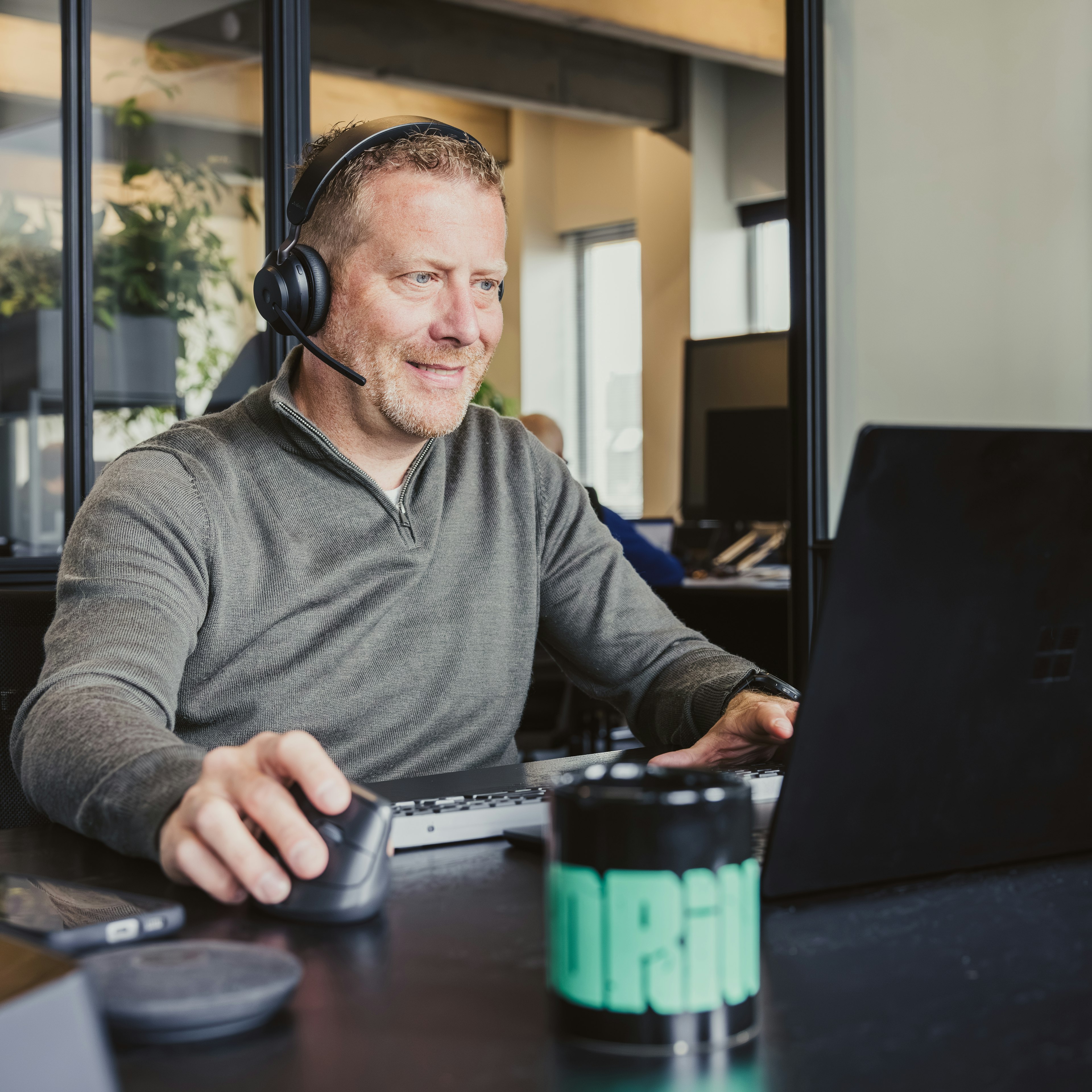 Man with a headset working at a laptop in an office