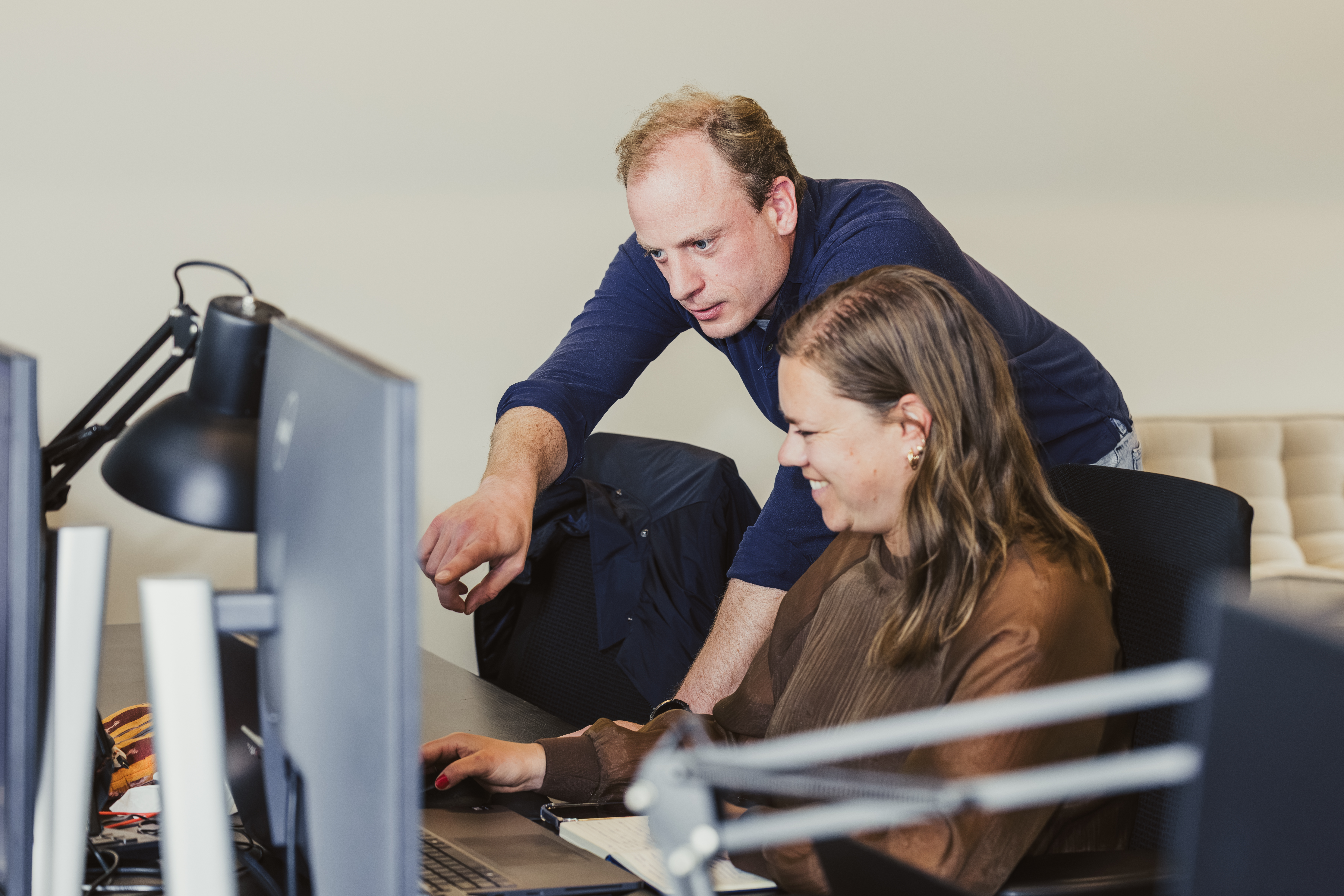 Two colleagues reviewing work on a computer screen