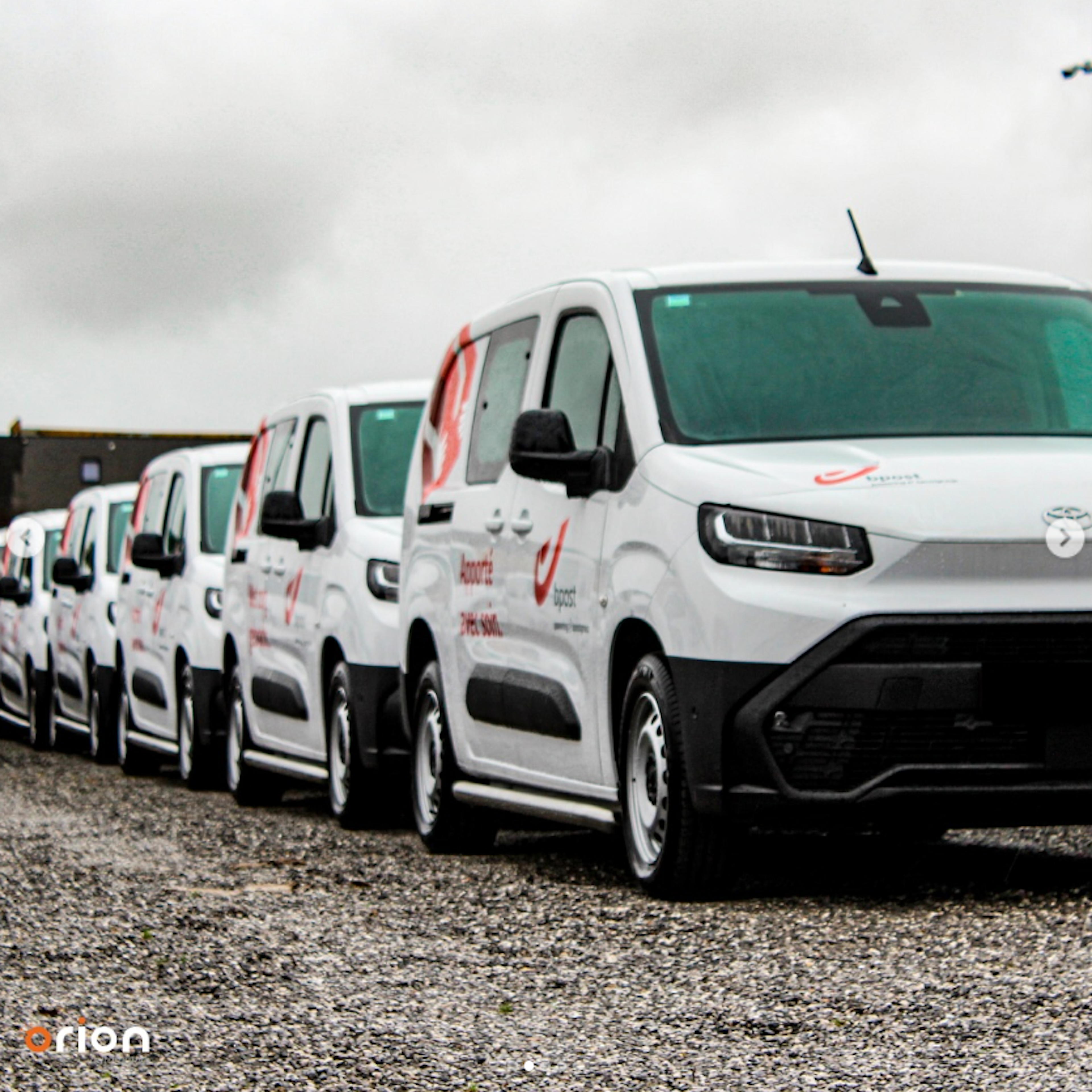 L'équipe d'Orion Automotive pose devant des véhicules aux couleurs de la marque, sous le logo de l'entreprise, à l'entrée de ses locaux.