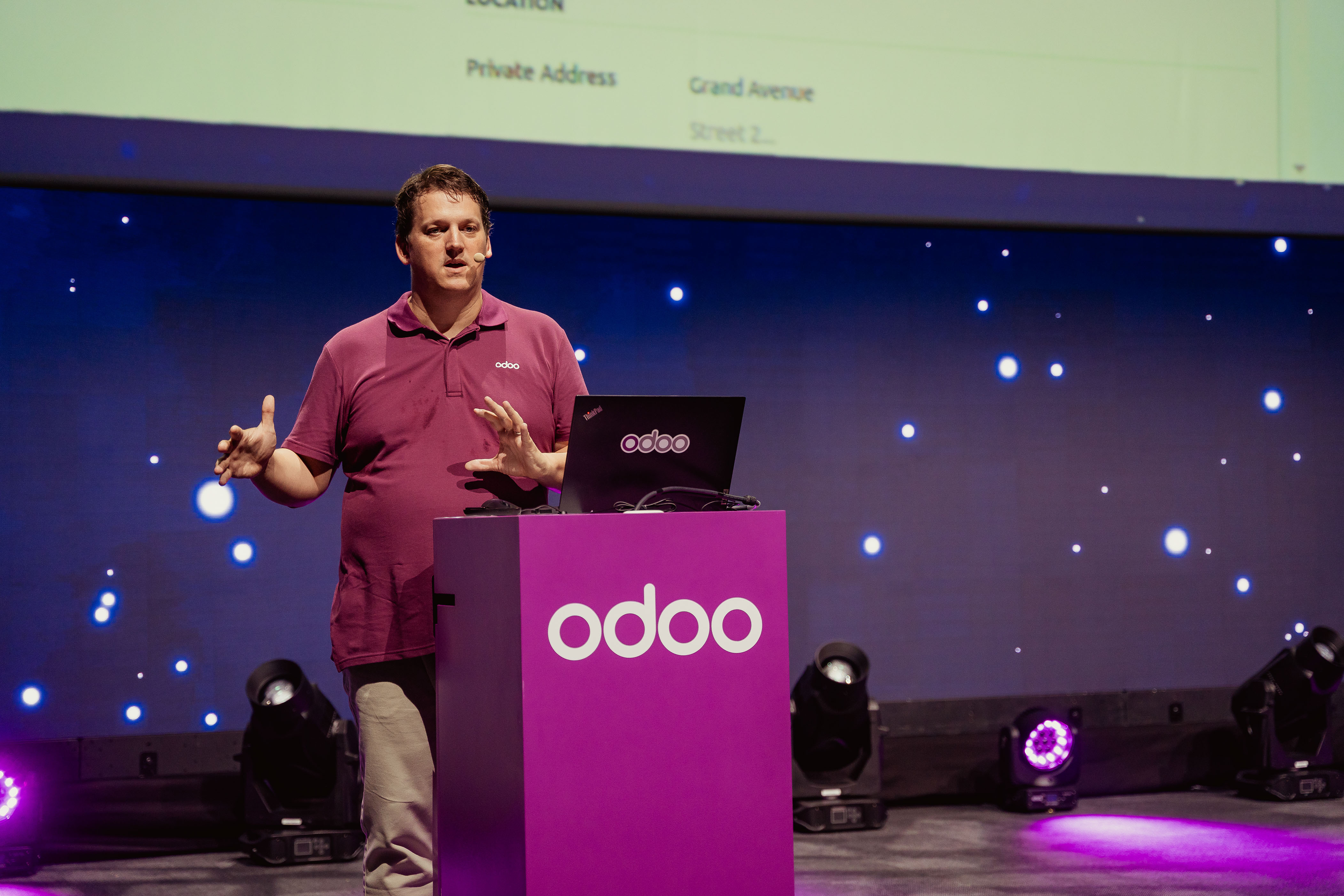 Speaker presenting at an Odoo-branded lectern on stage
