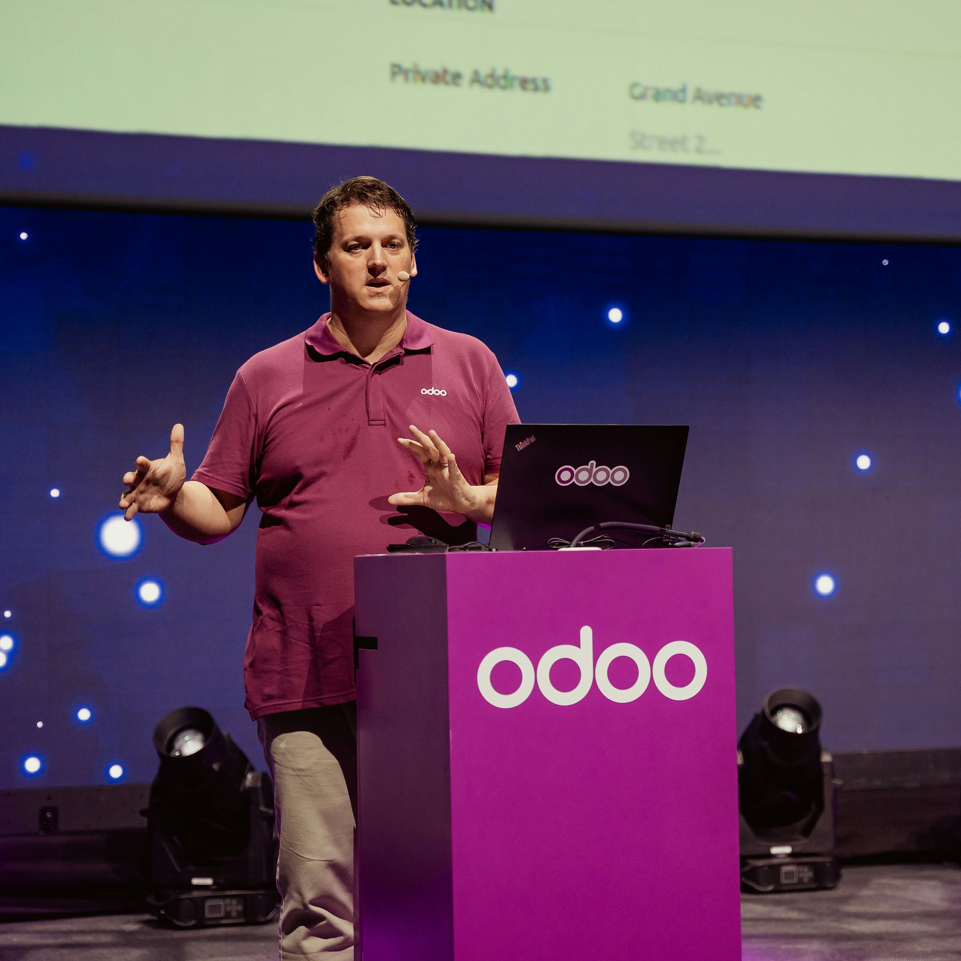 Speaker presenting at an Odoo-branded lectern on stage