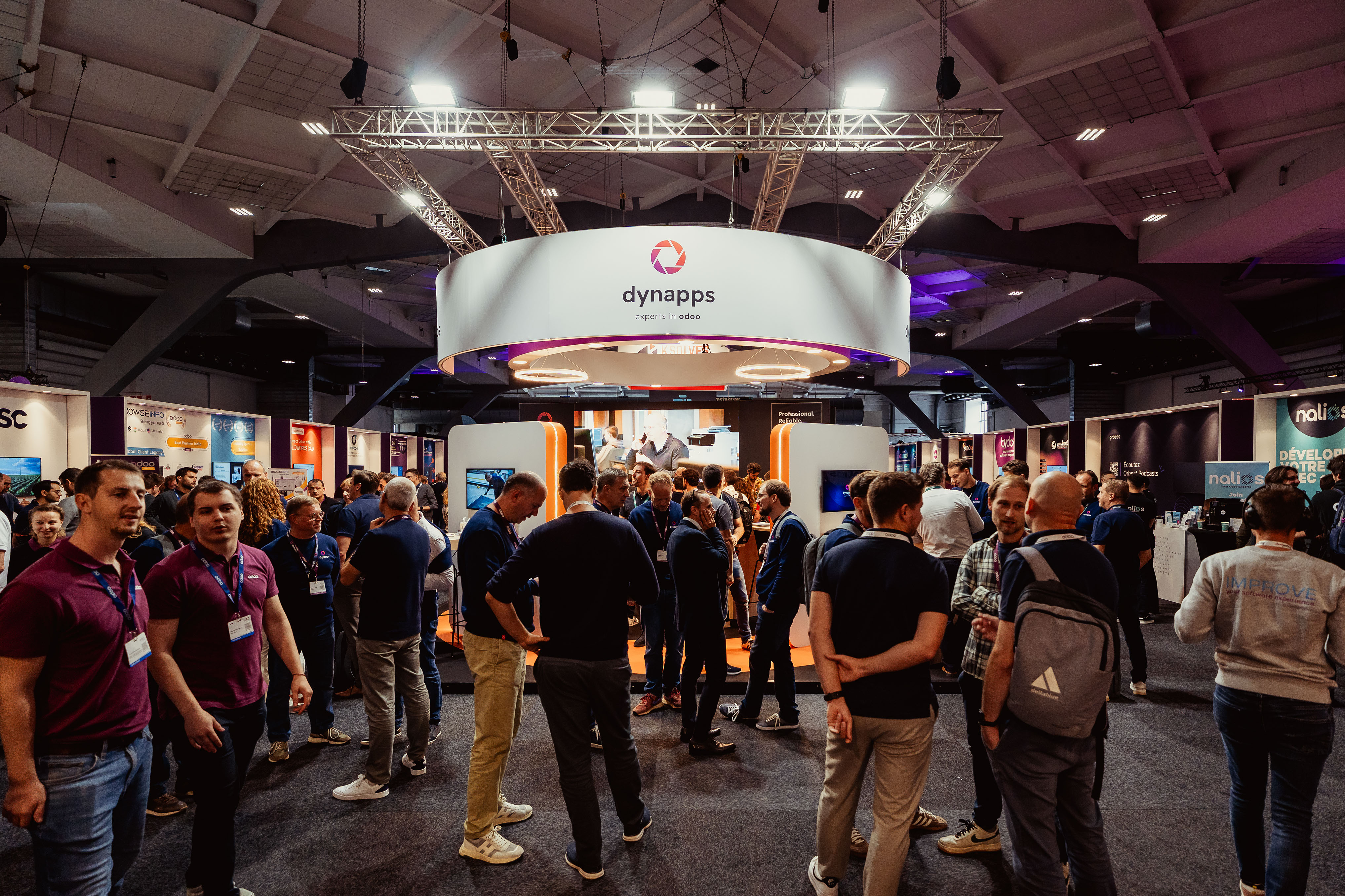 Visitors gathering around the circular Dynapps booth at a trade fair
