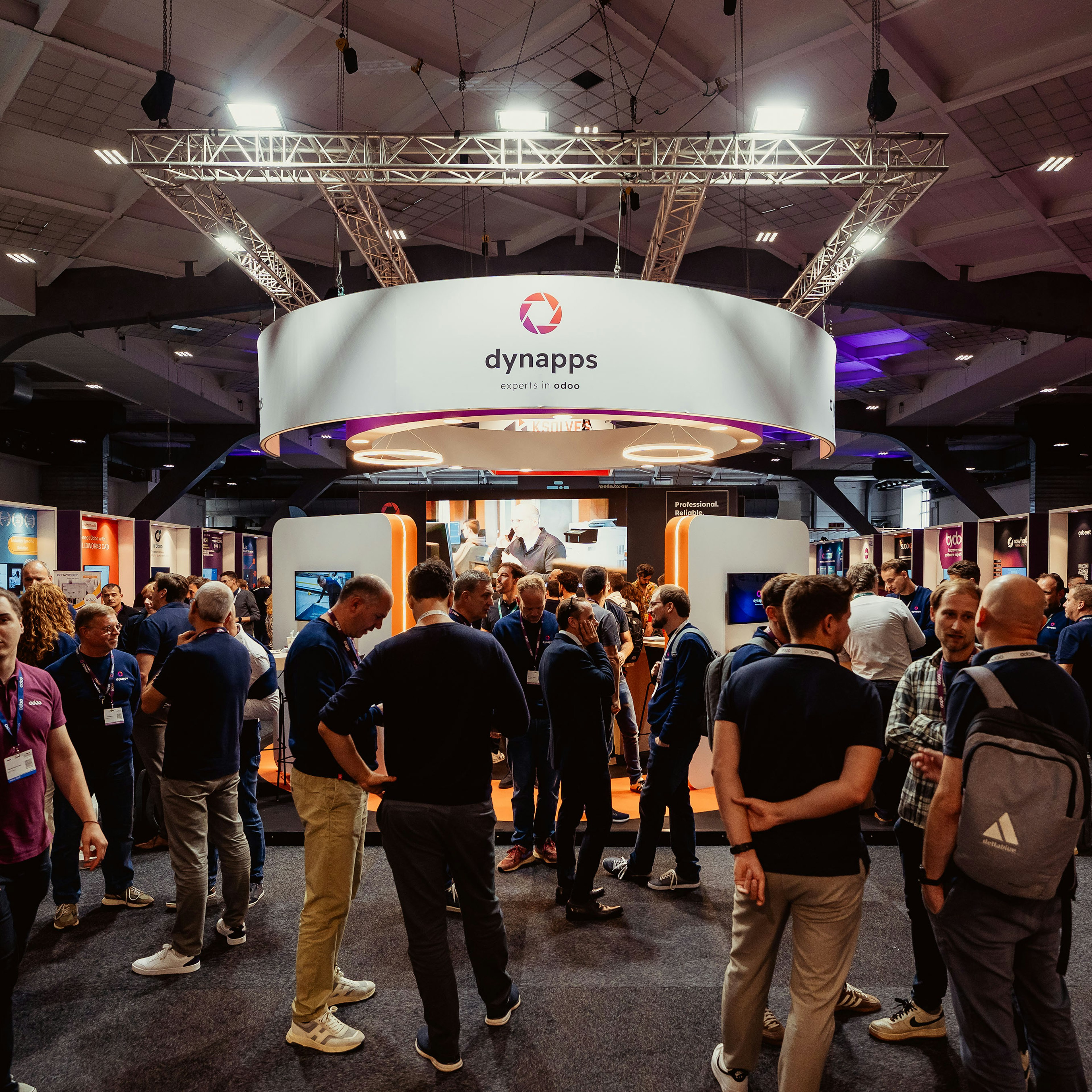 Visitors gathering around the circular Dynapps booth at a trade fair