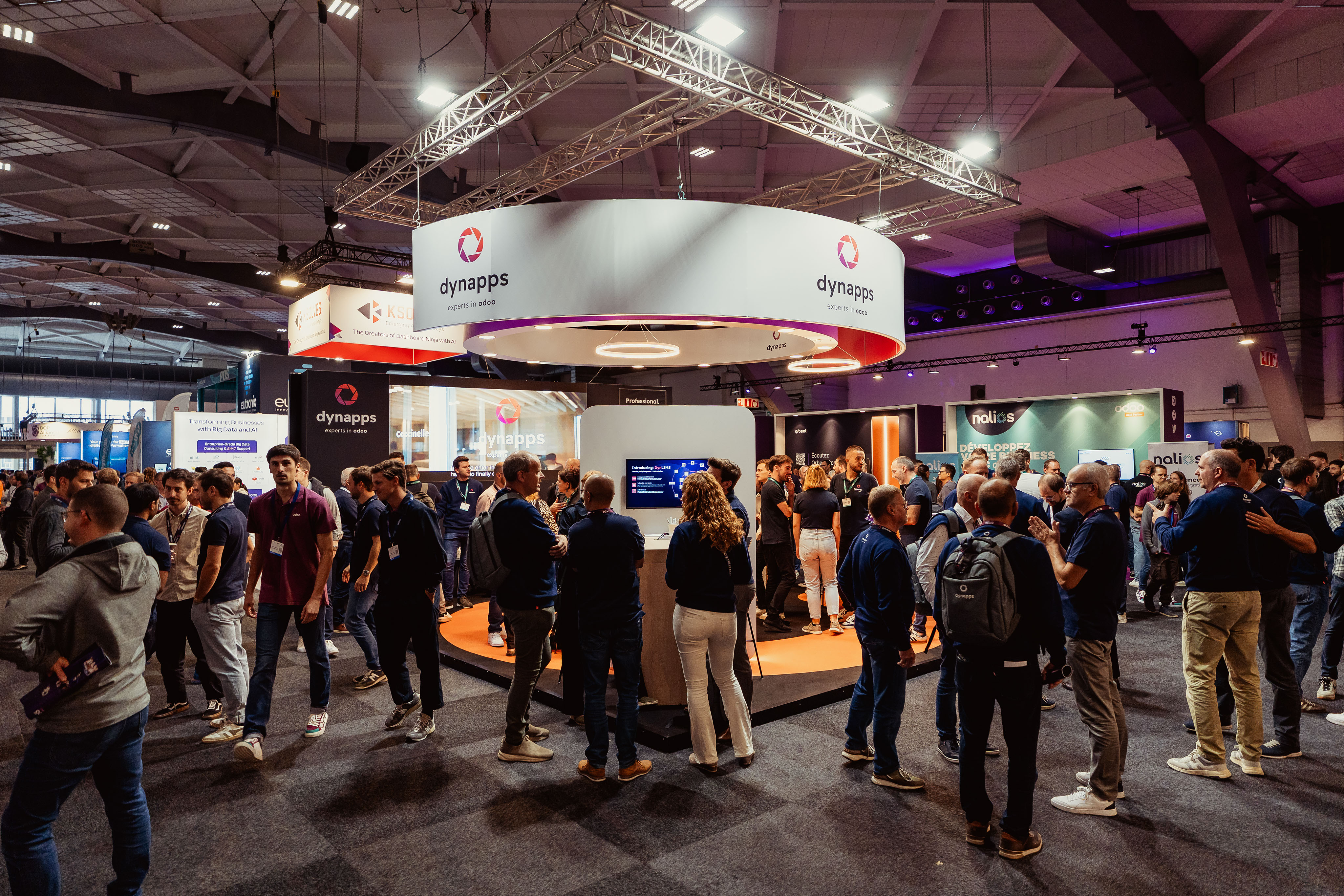 Crowded exhibition floor around the Dynapps stand with demo screens