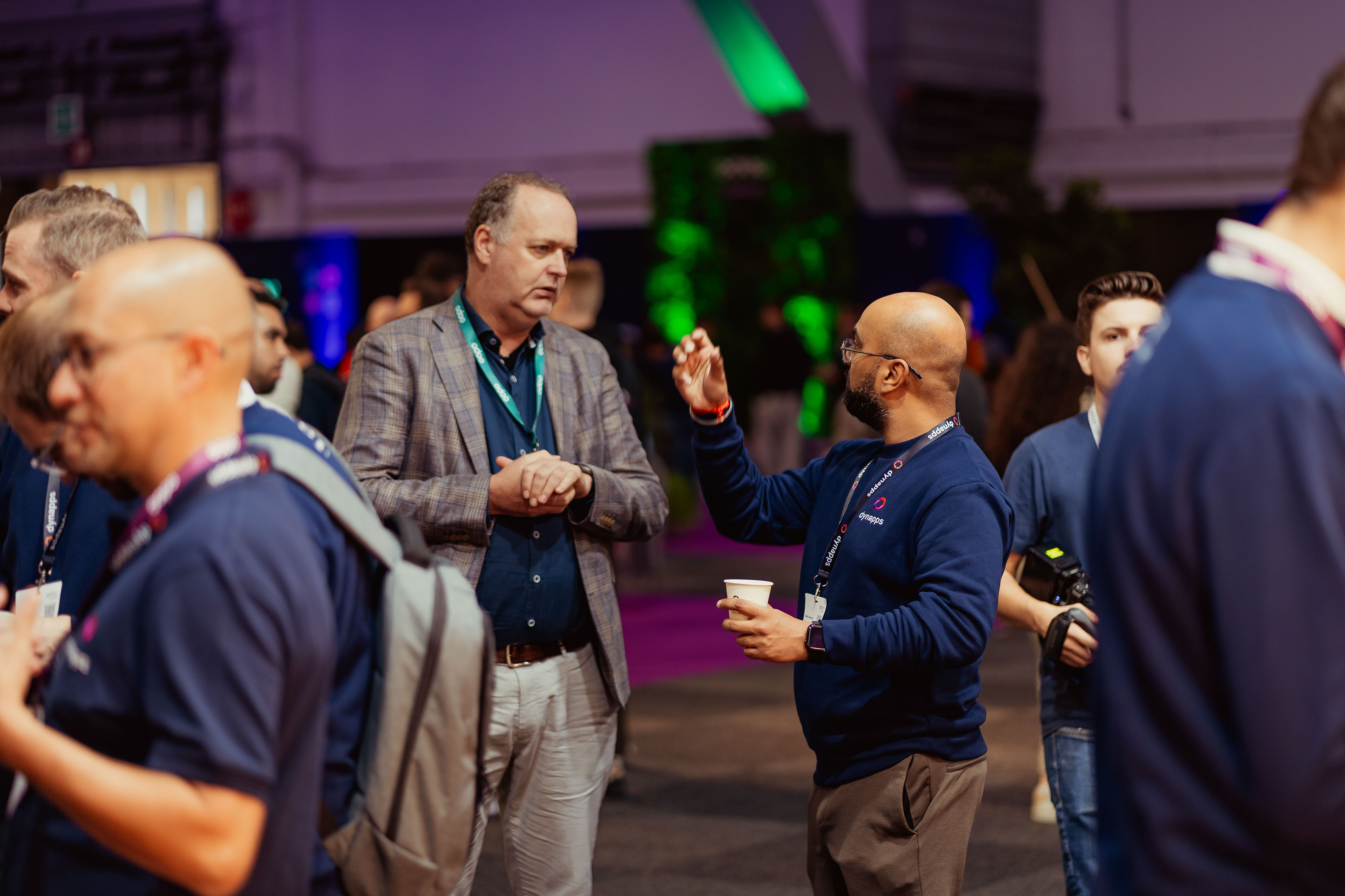 Attendees with coffee in conversation on the exhibition floor