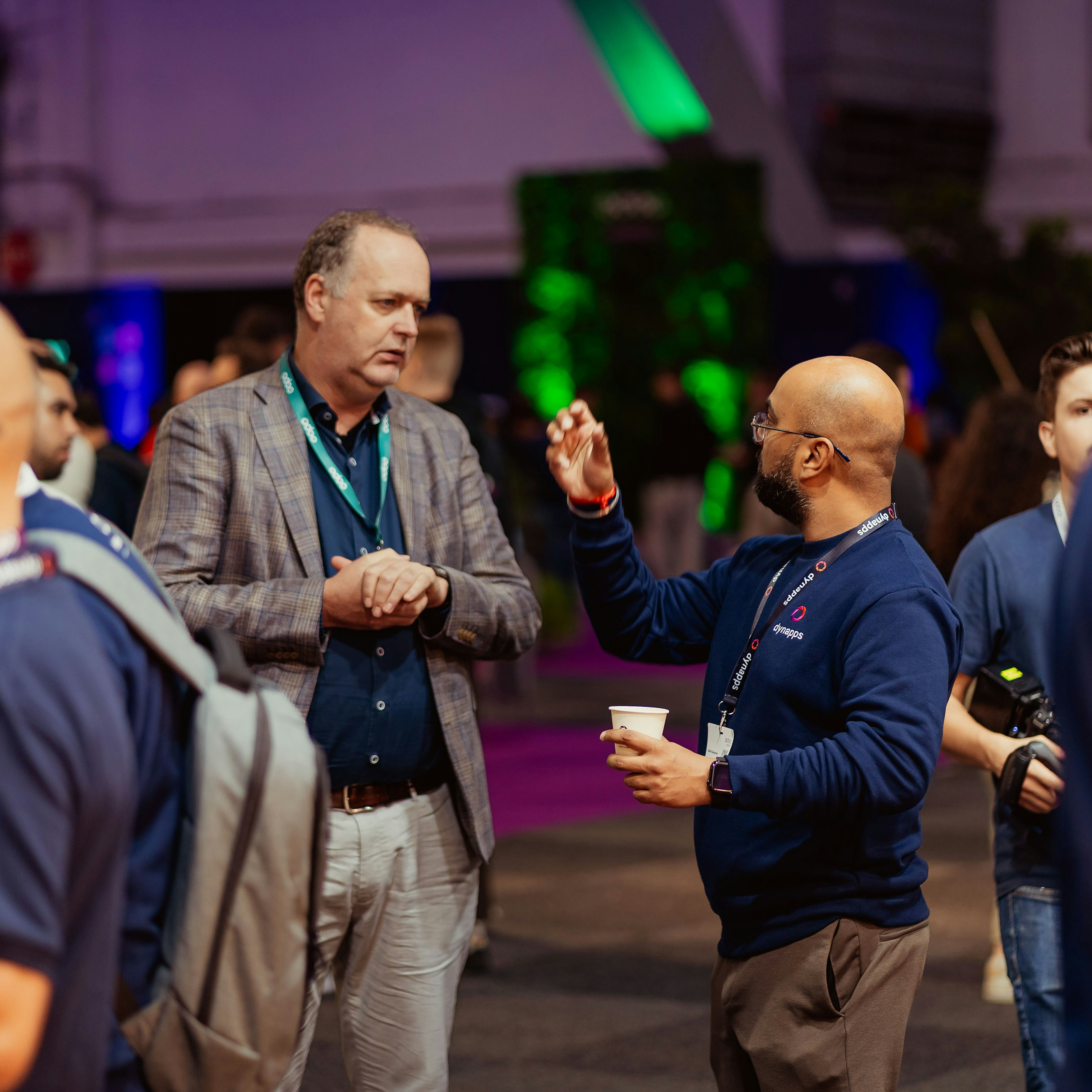 Attendees with coffee in conversation on the exhibition floor