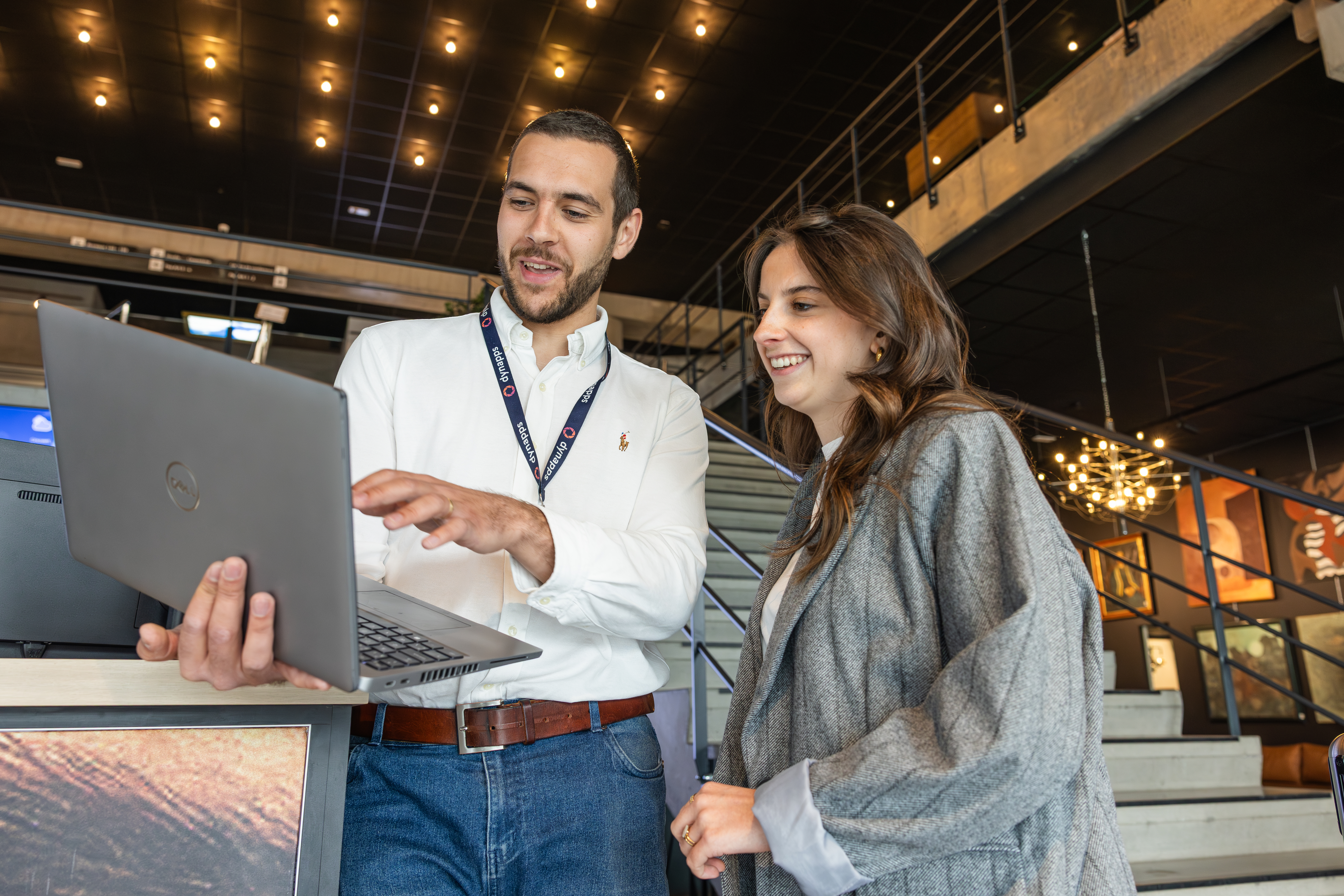 Consultant showing a laptop screen to a smiling visitor
