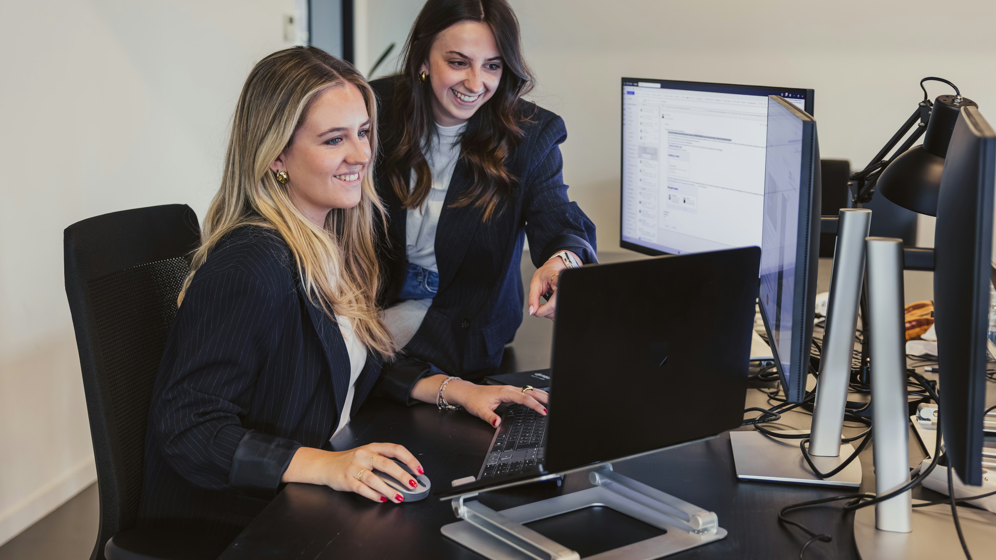 Twee vrouwen die achter een bureau software op een scherm bekijken