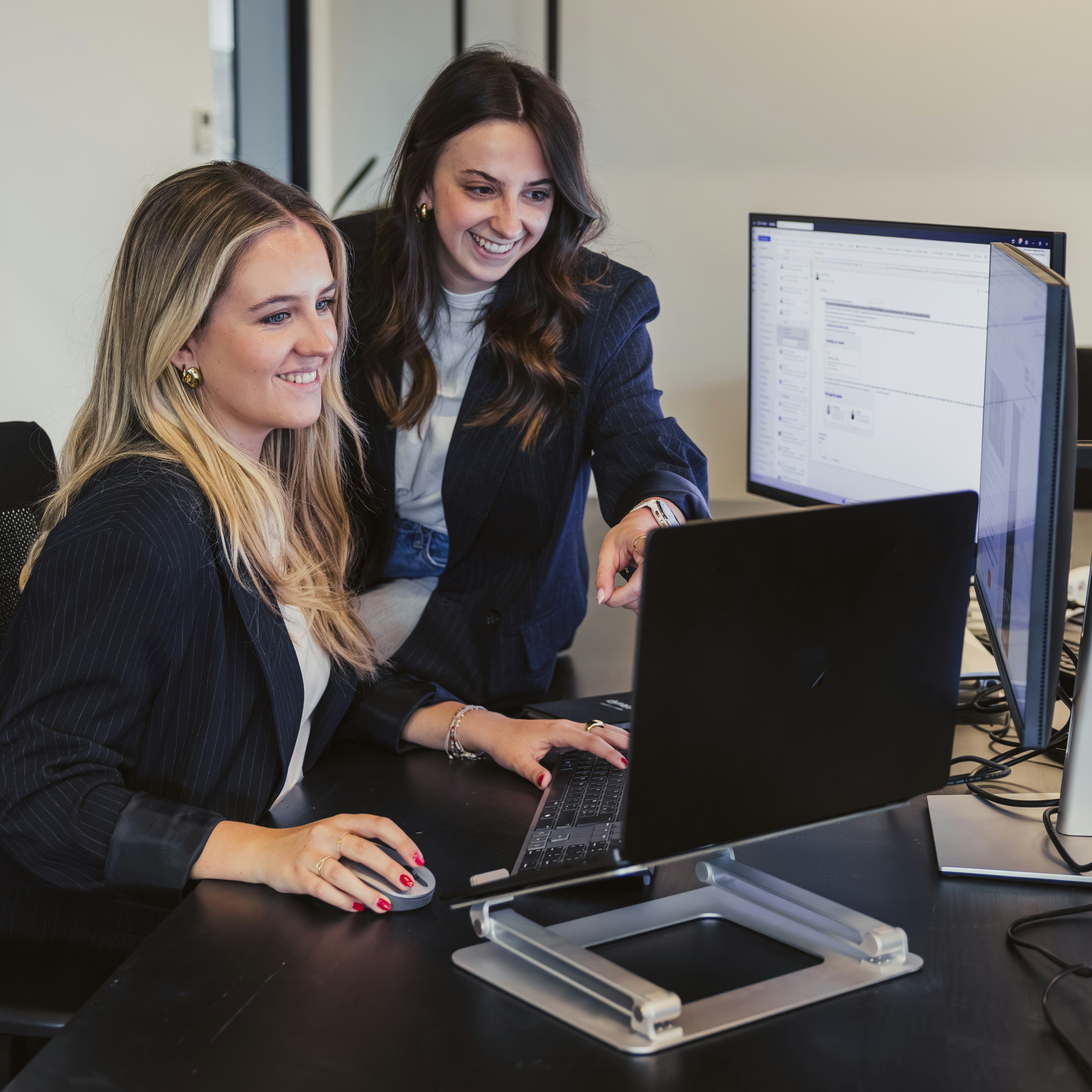 Two women reviewing software on a screen at a desk