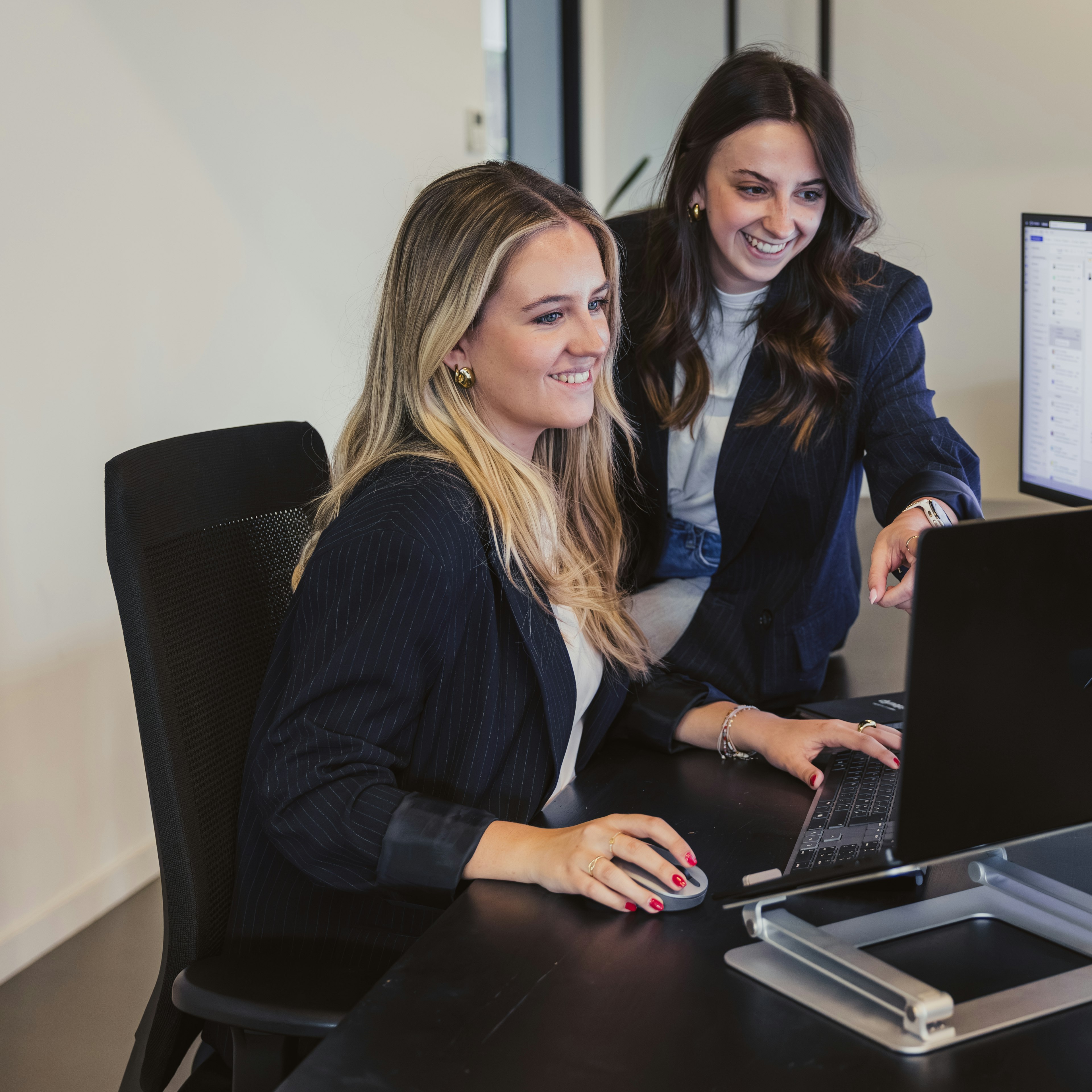 Two woman reviewing software on a screen on a desk