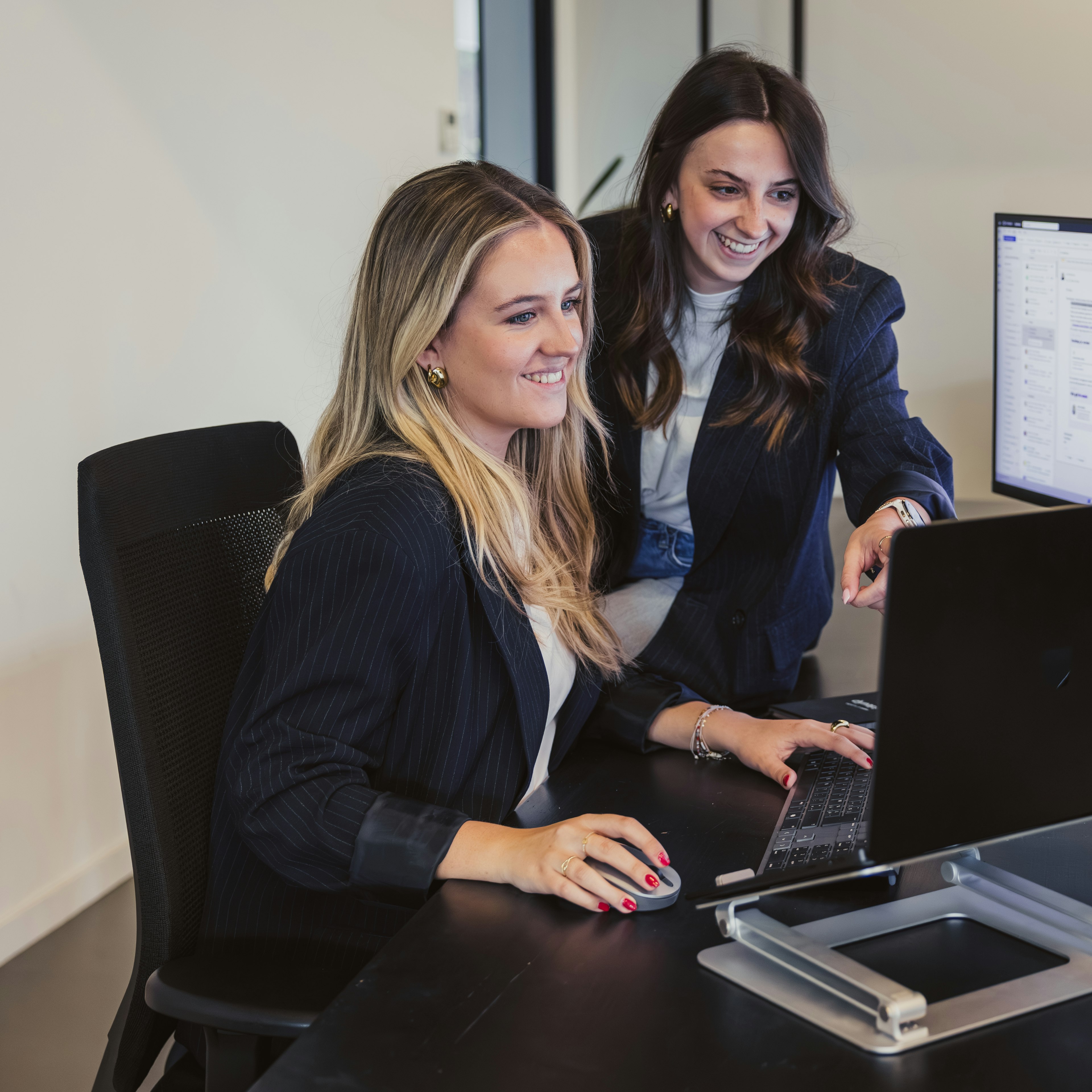 Two woman reviewing software on a screen on a desk