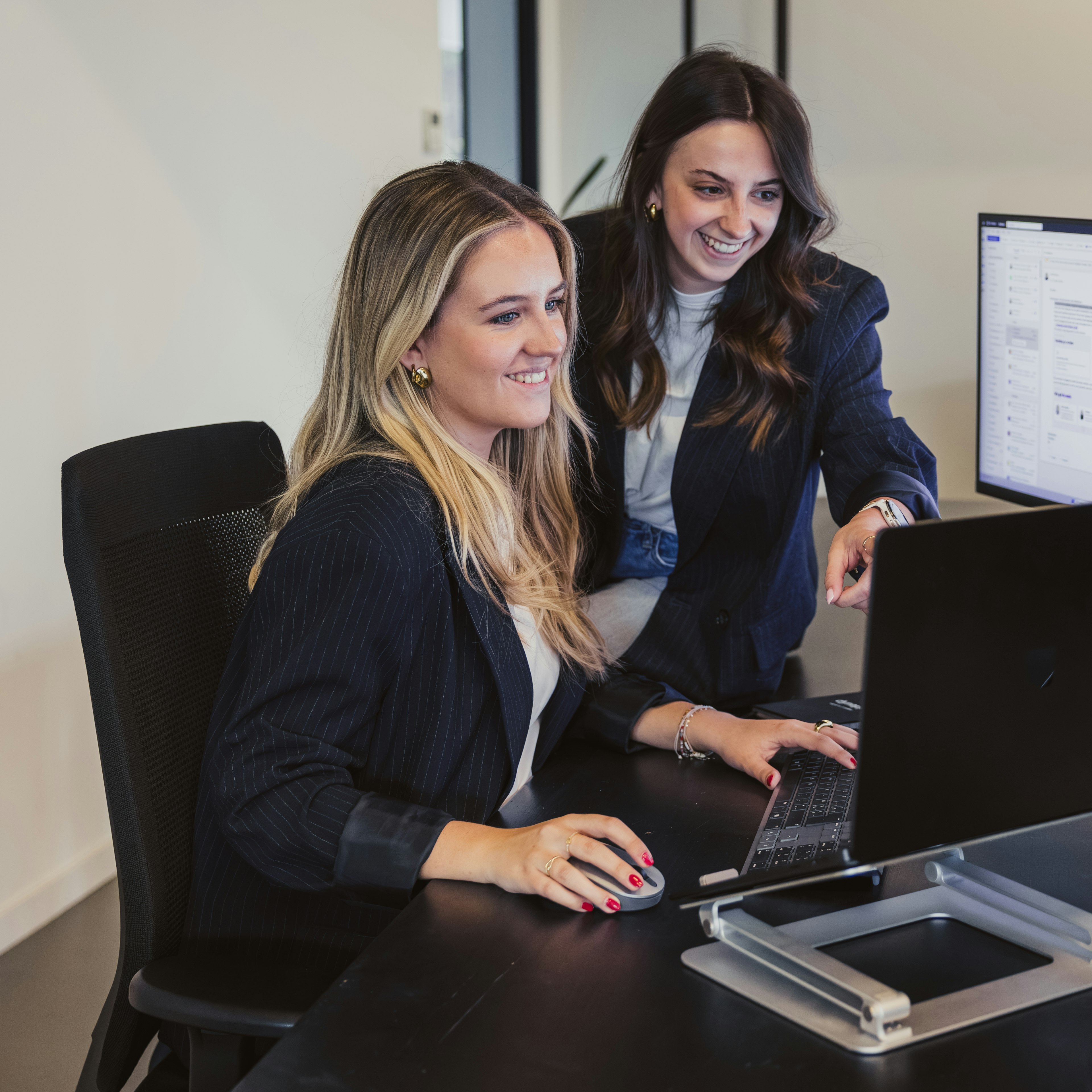 Two woman reviewing software on a screen on a desk