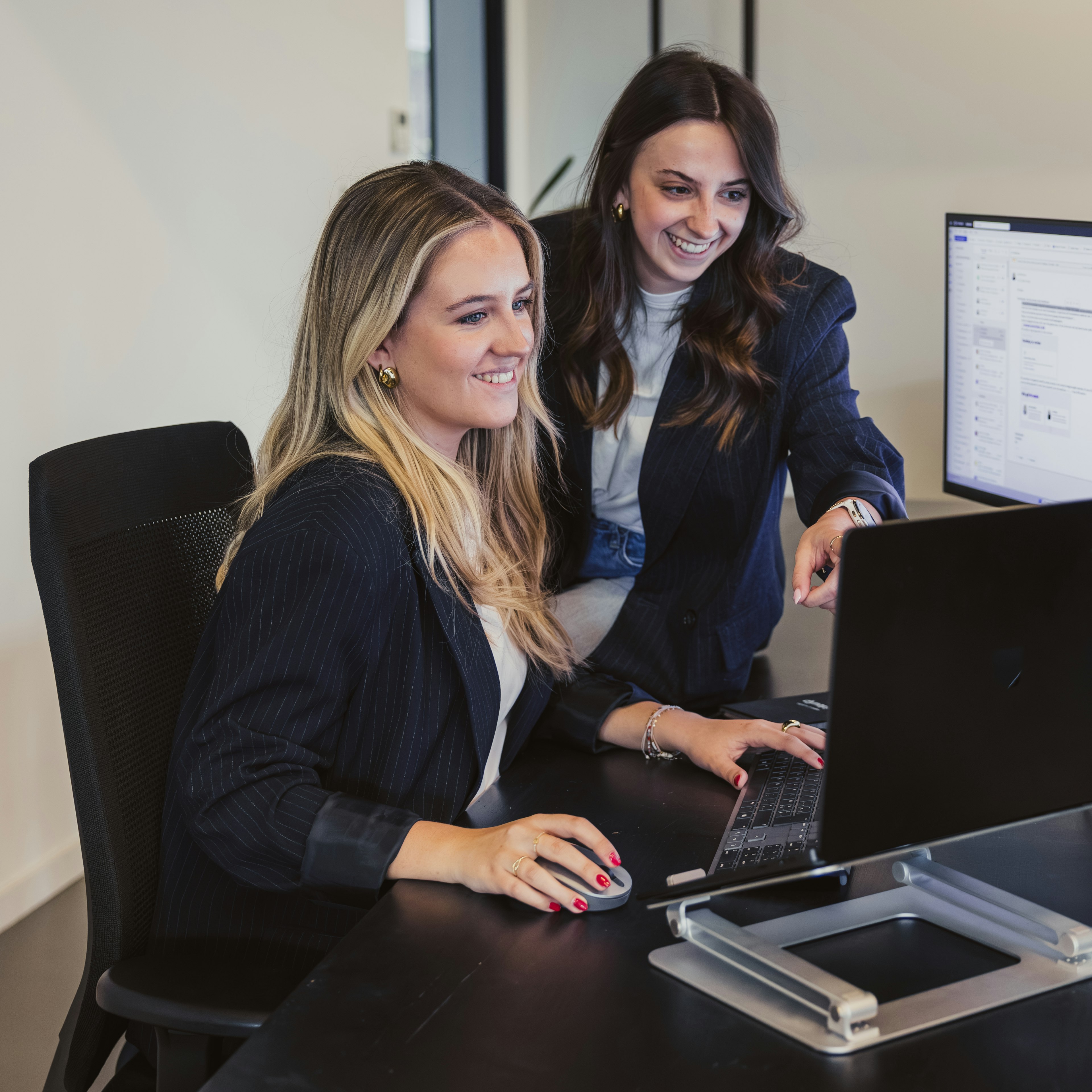 Two woman reviewing software on a screen on a desk