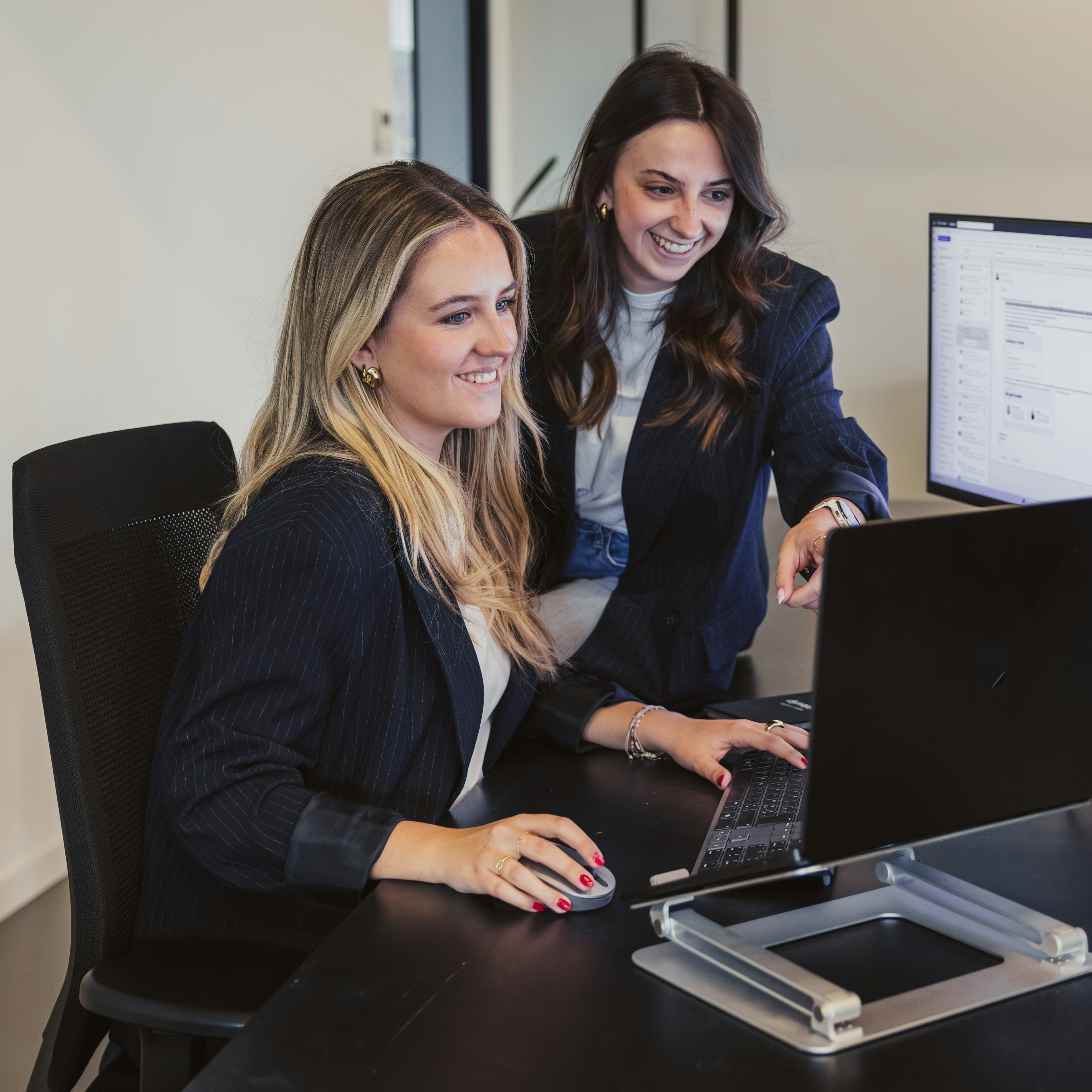 Two women reviewing software on a screen at a desk