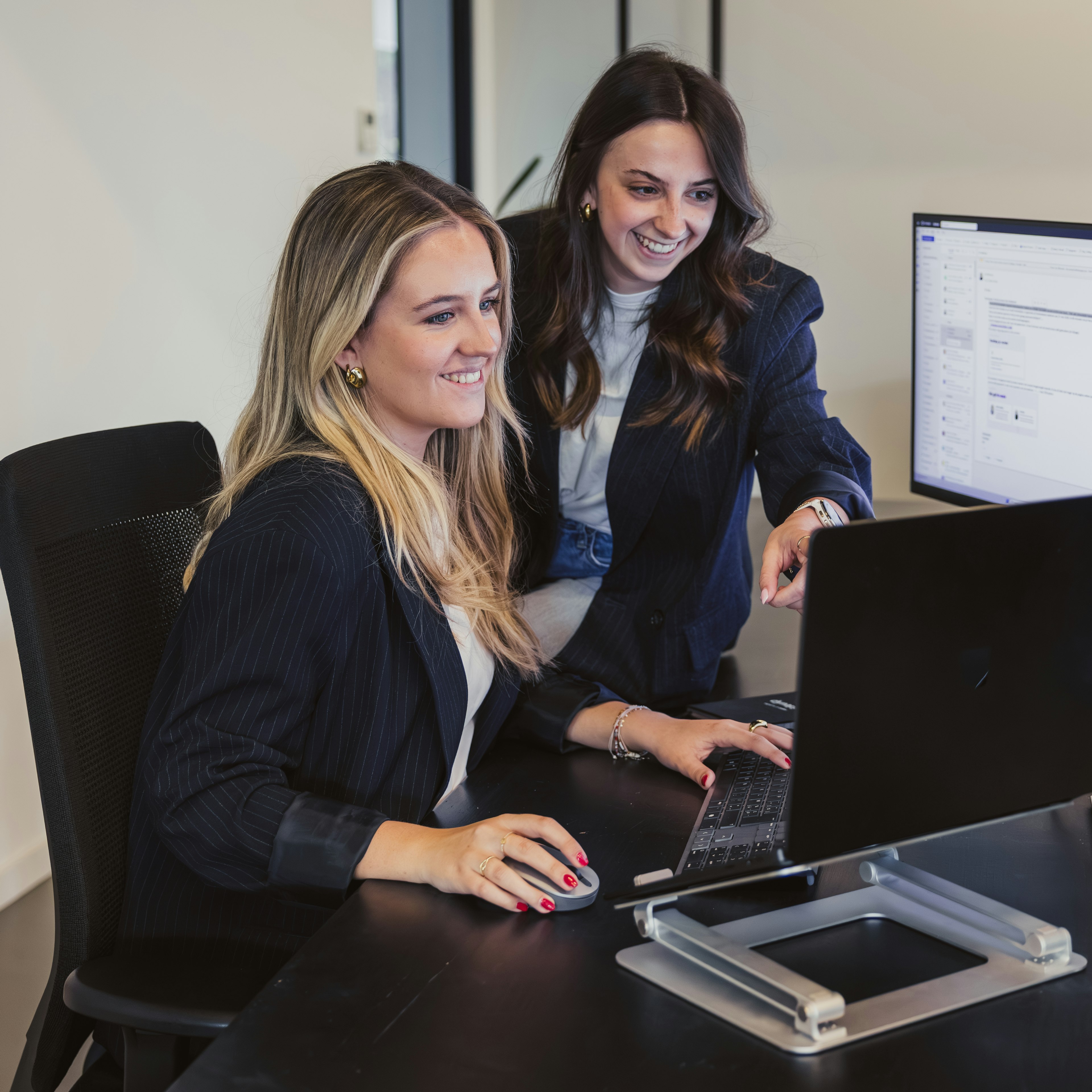 Two woman reviewing software on a screen on a desk