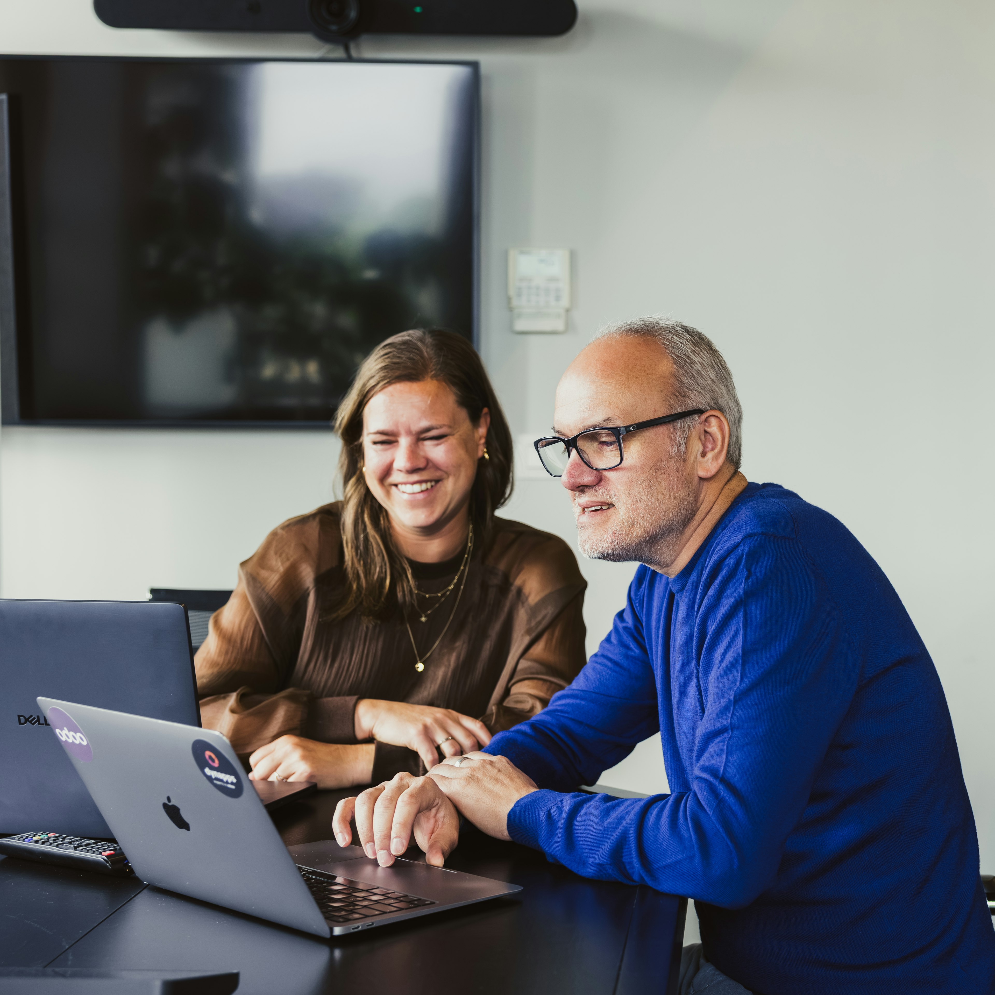 Two smiling colleagues working on a laptop together