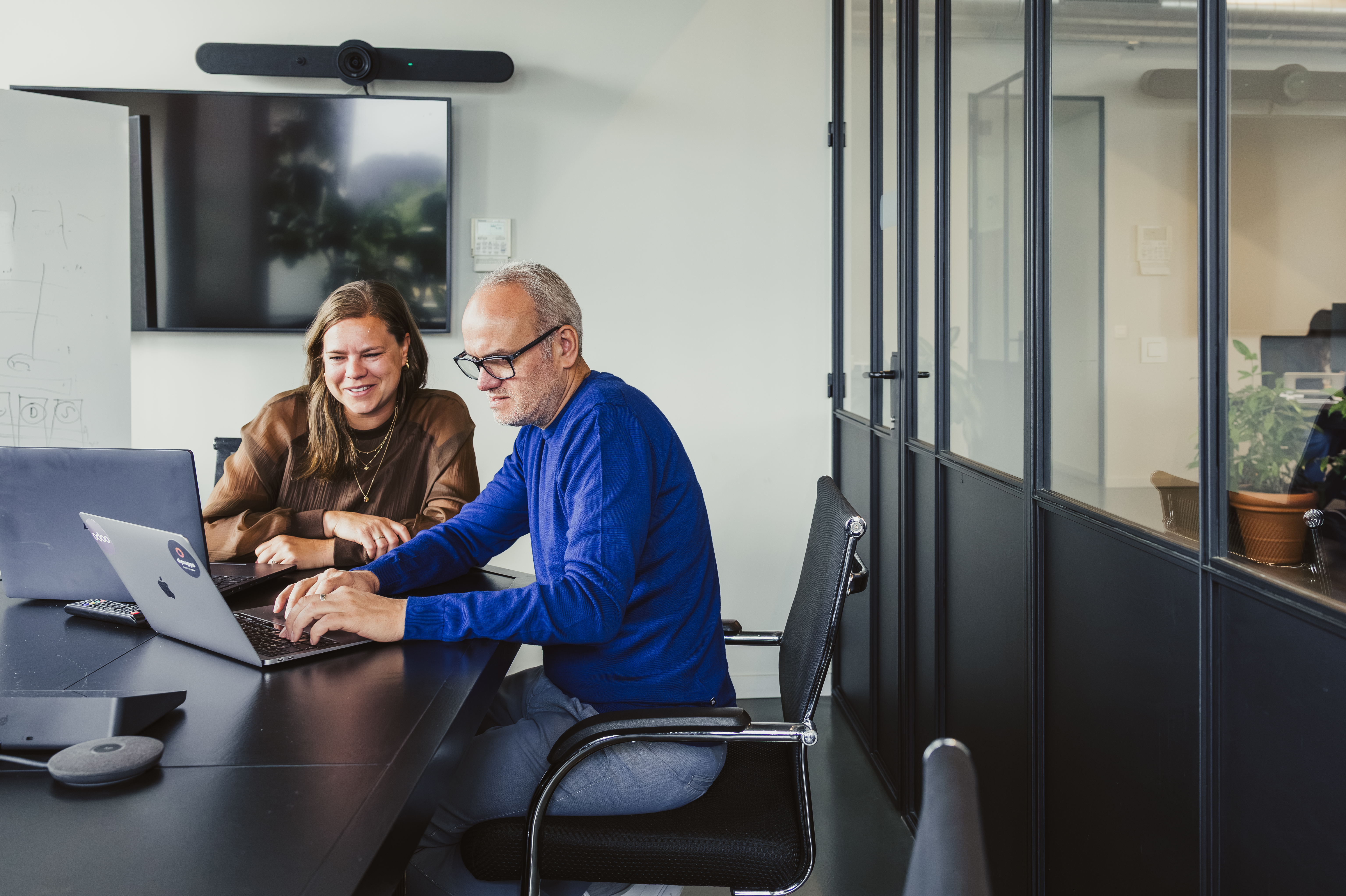 Two colleagues collaborating on a laptop in a meeting room