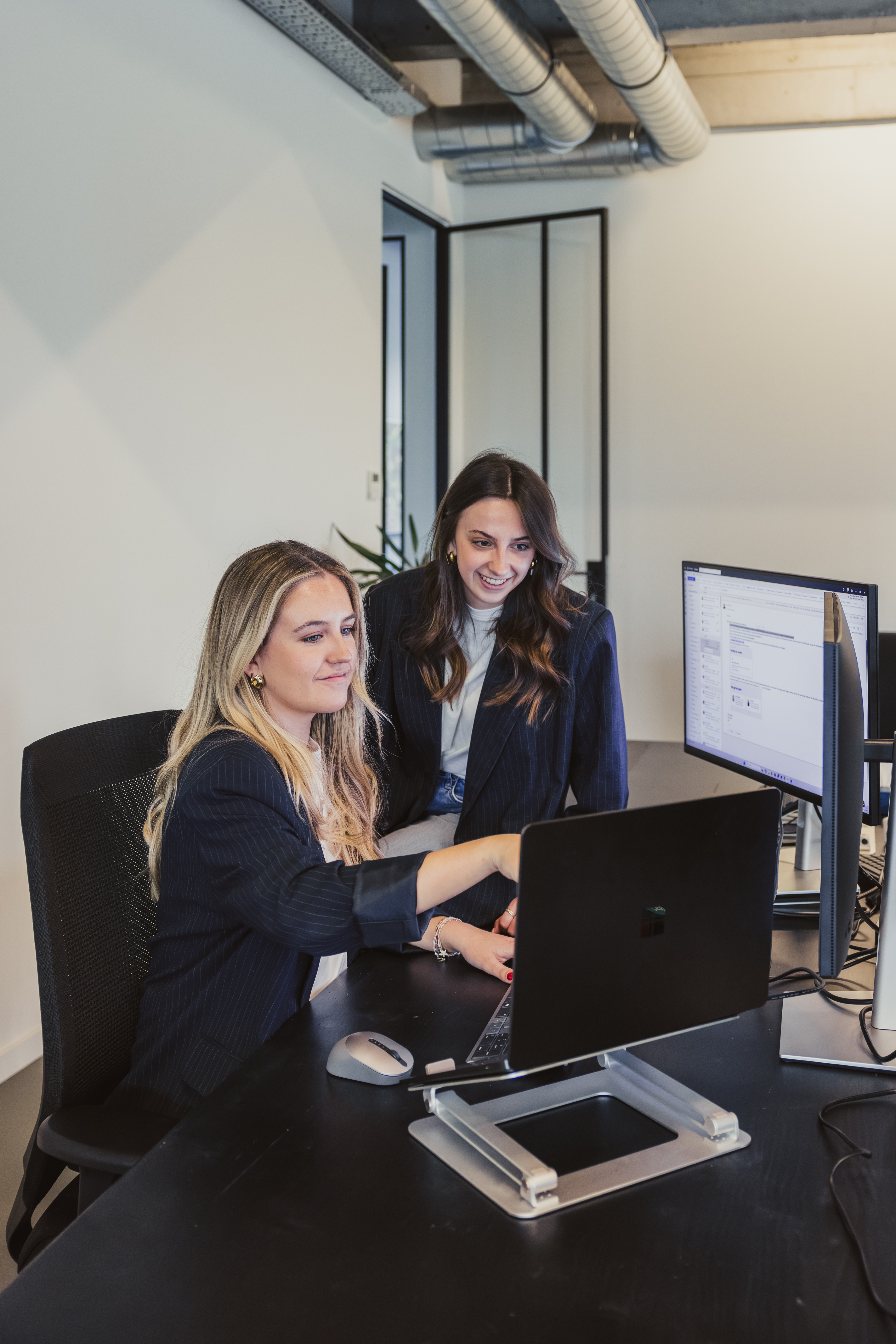 Colleague guiding a coworker at a dual-screen workstation